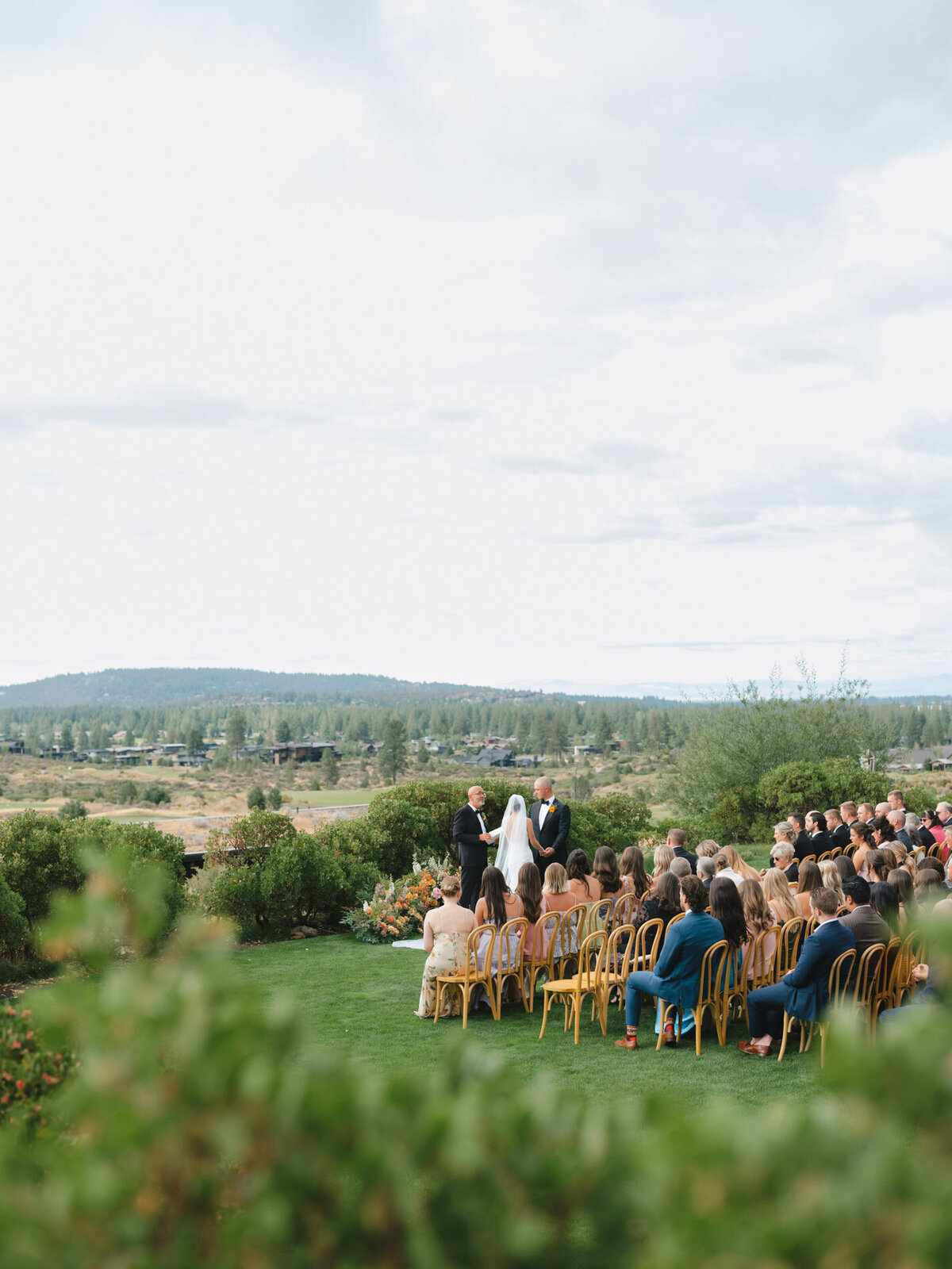 modern wedding ceremony at a mountain venue in oregon with wood chairs and guests representing full service design and calligraphy by Life in Letters.