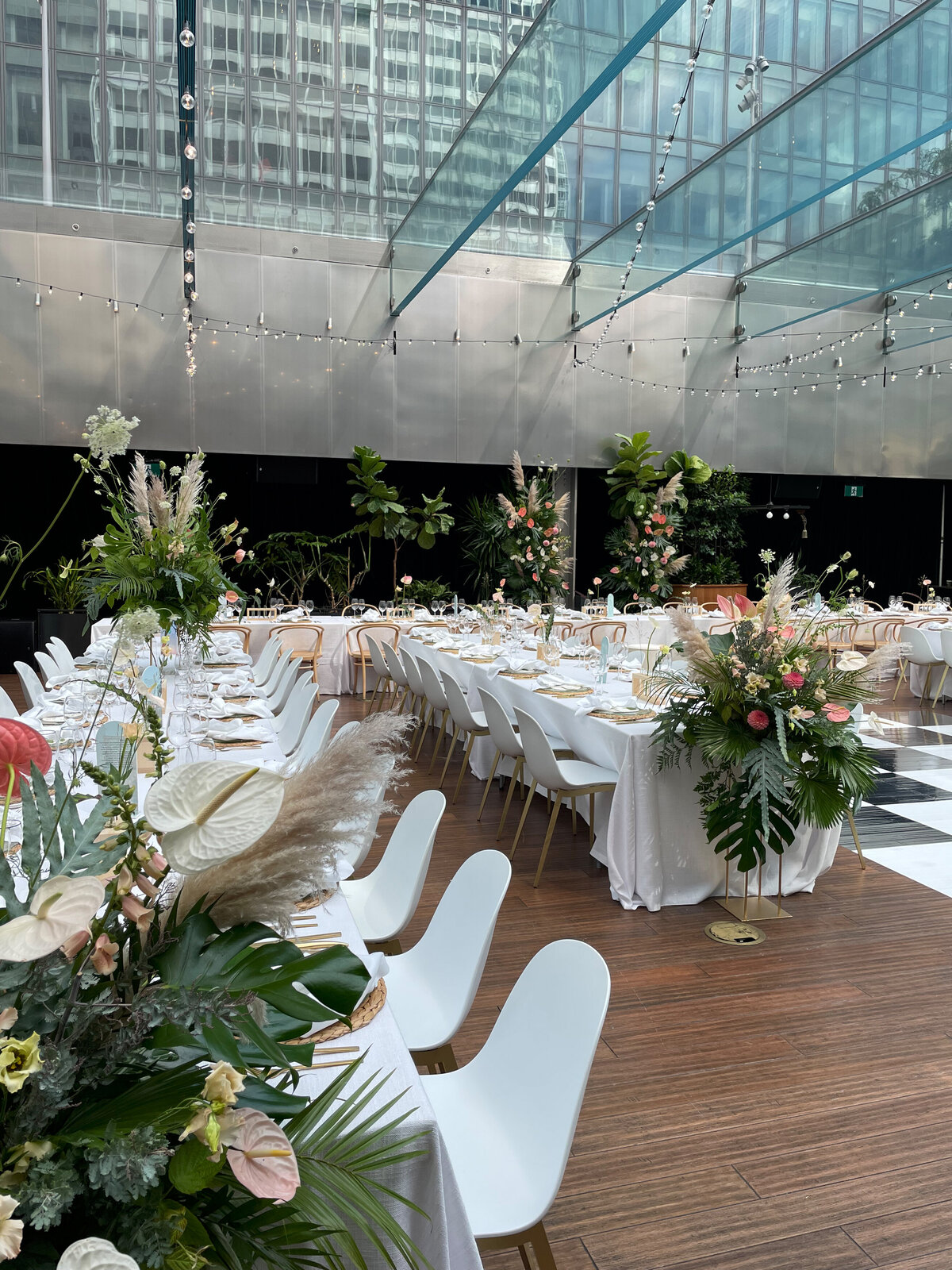 Under the glass roof of the Cathcart, tables are decorated with exotic wedding flowers. 