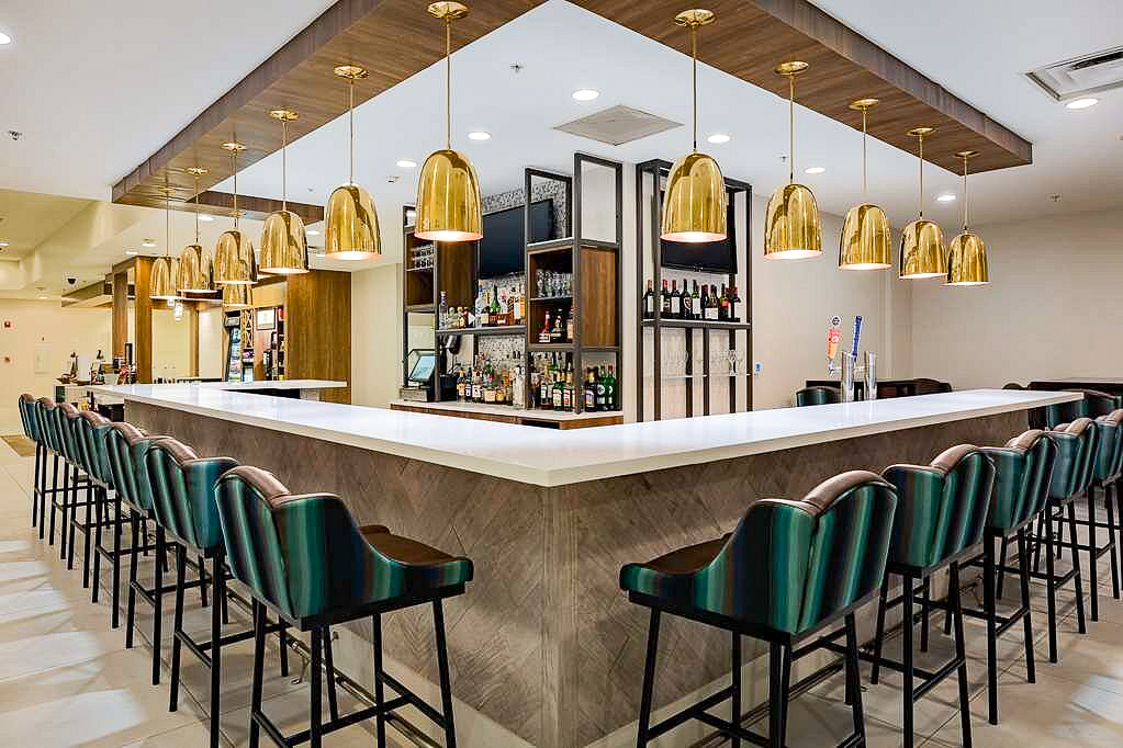 Sleek and modern hotel bar with gold pendant lights and turquoise accents