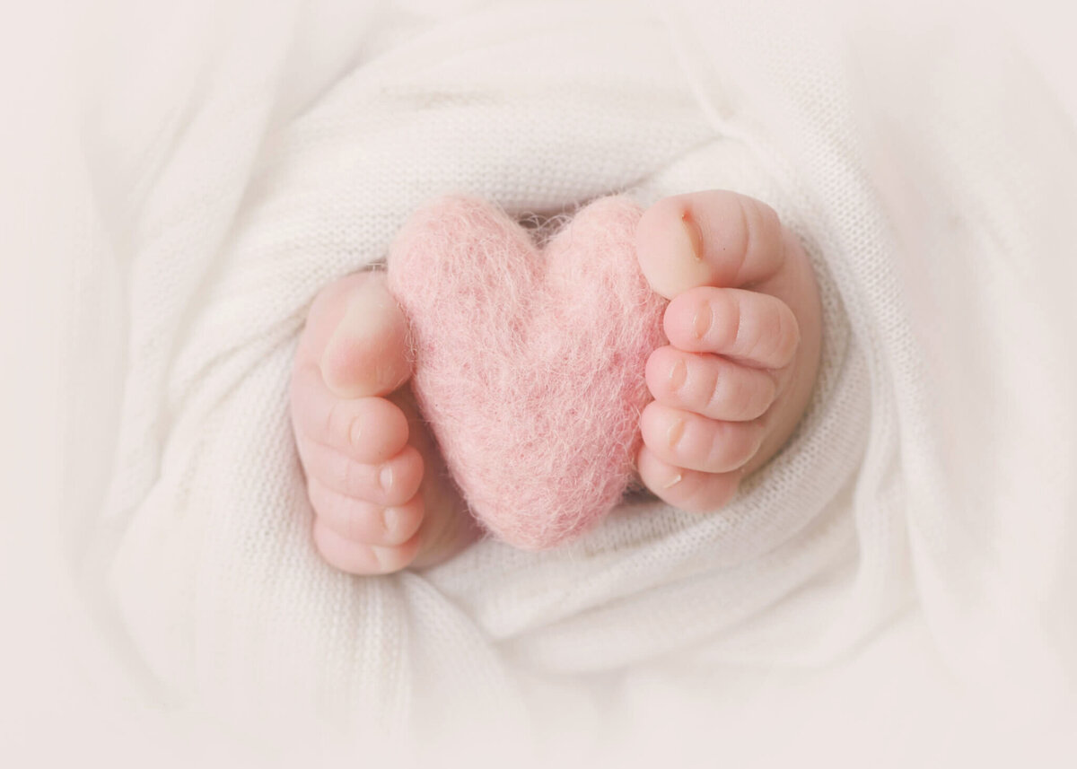 Baby toes holding a heart teddy