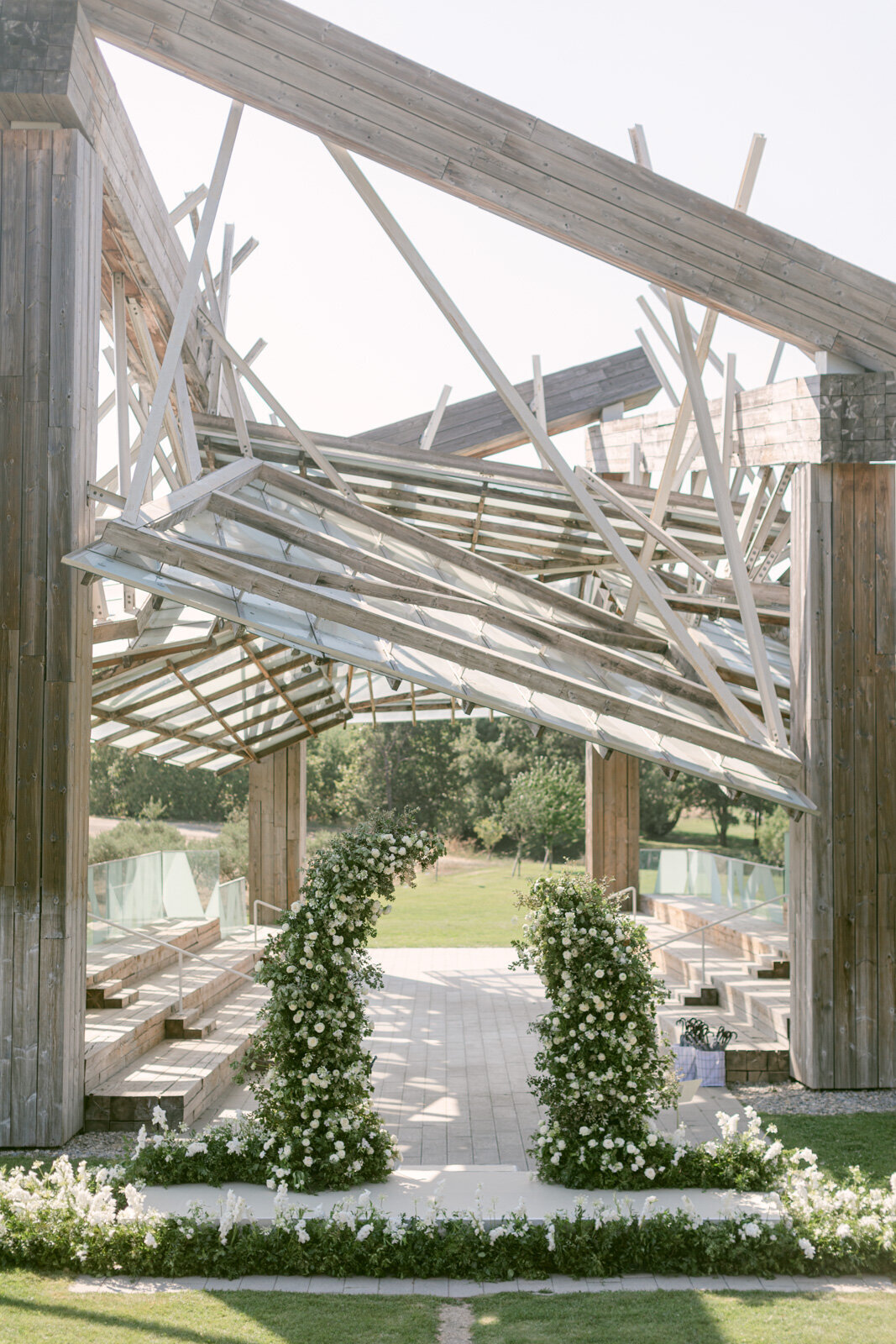 Modern outdoor wedding ceremony structure in Château Lacoste Provence decorated with elegant white floral arches.