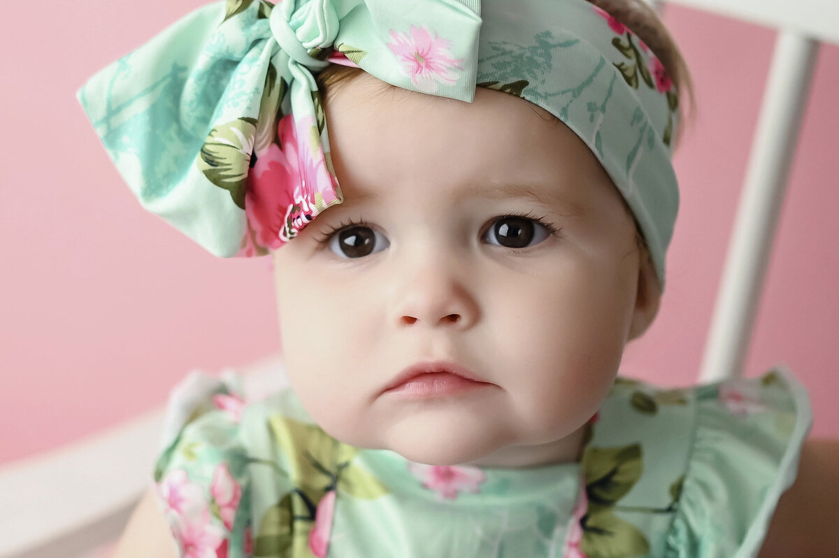 Dramatic close up photo of a baby wearing a floral headband
