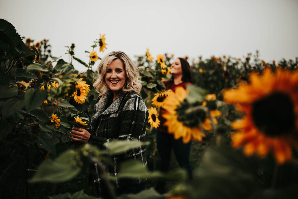 women standing in a field of sunflowers