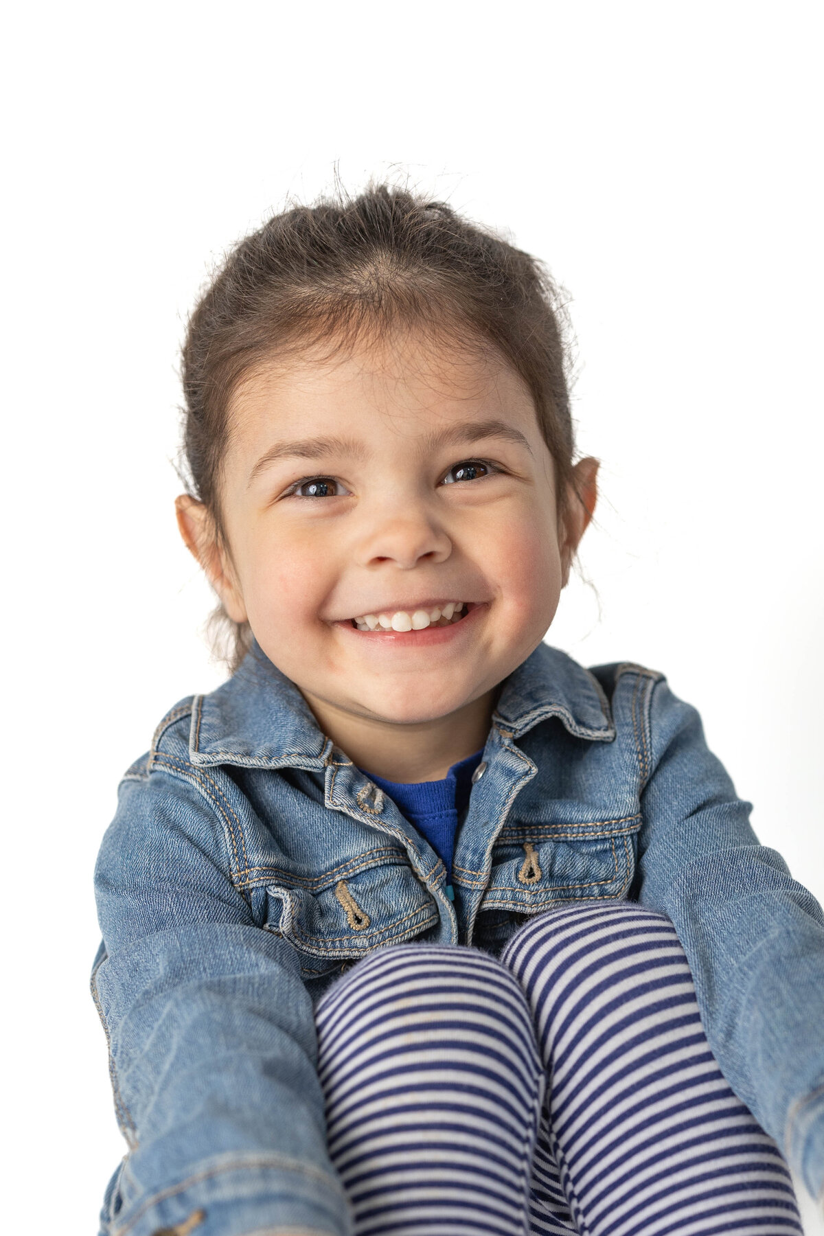 Three year old girl in jean jacket sits comfortably for her school photo
