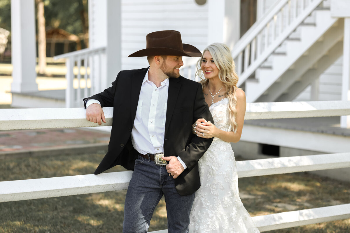 bride and groom looking at each other wearing lace dress, blue jeans and ariat cowboy hat in Phenix City Alabama by Columbus Georgia wedding photographer Amanda Richardson Photography