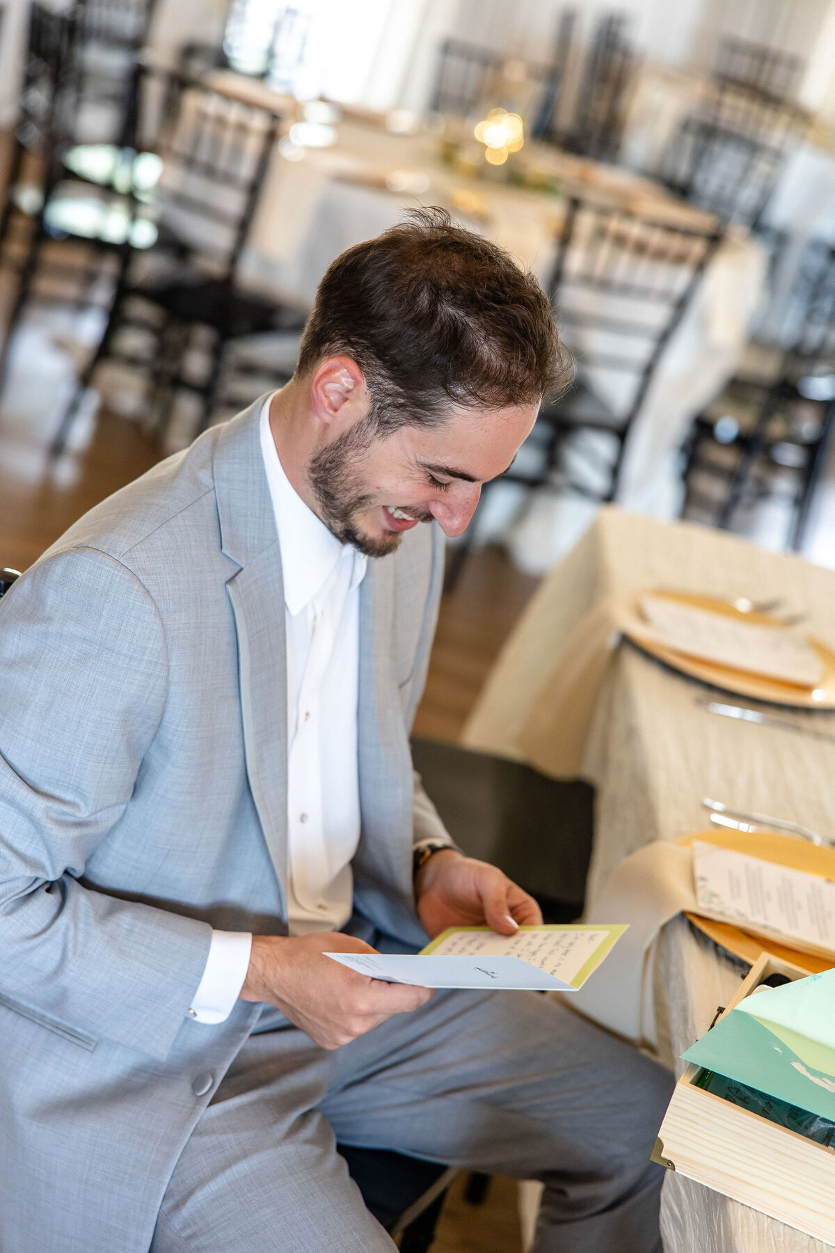 groom opens gift from bride at Milestone Georgetown Texas wedding in gray suit