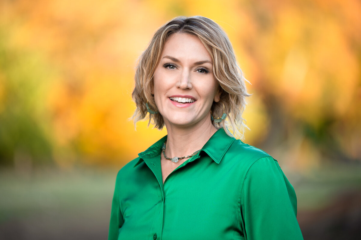 Headshot of woman in green shirt and orange background