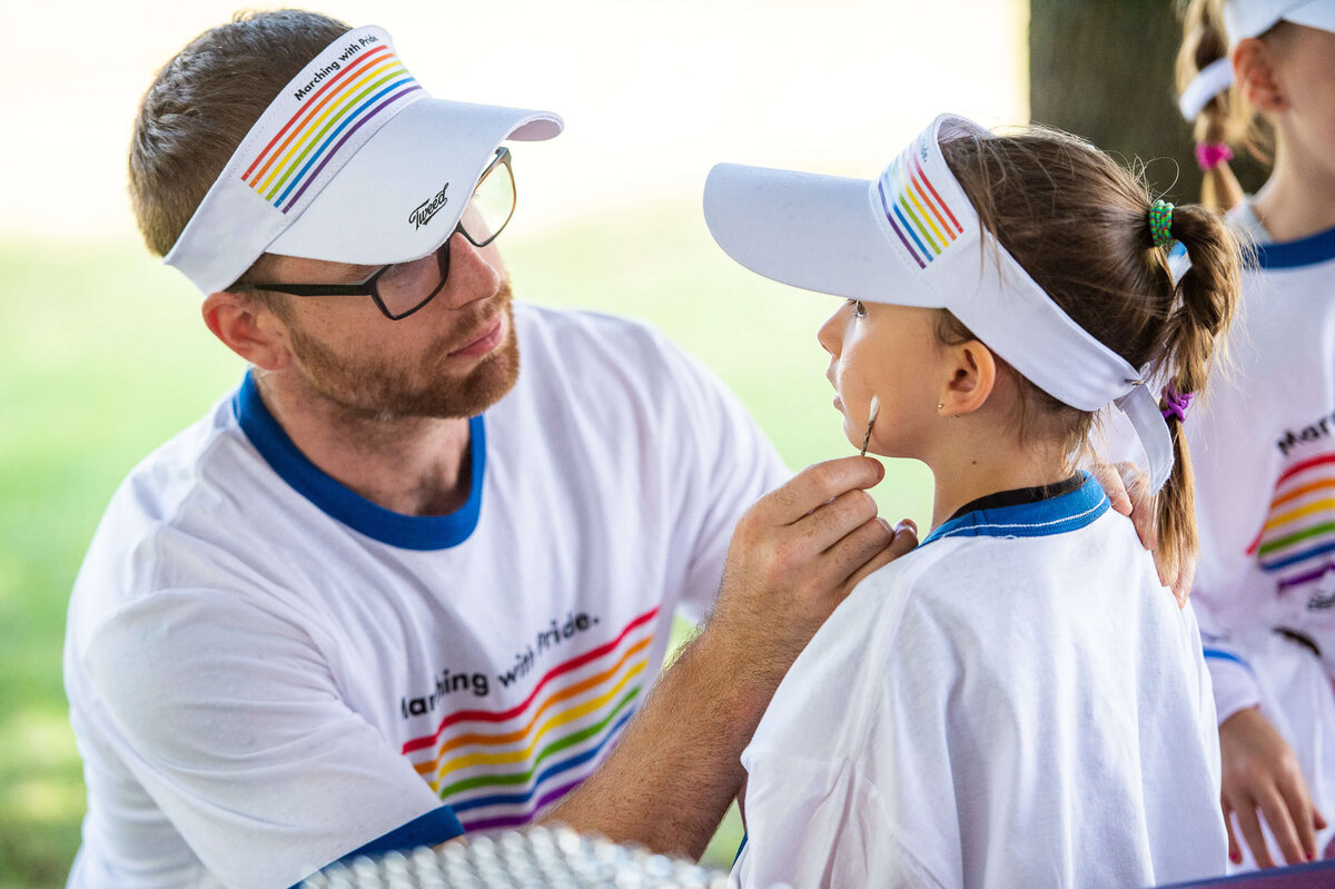 Ottawa event photography of a father putting face makeup on his child during the Tweed Canopy Growth Pride Parade. Captured by JEMMAN Photography COMMERCIAL 