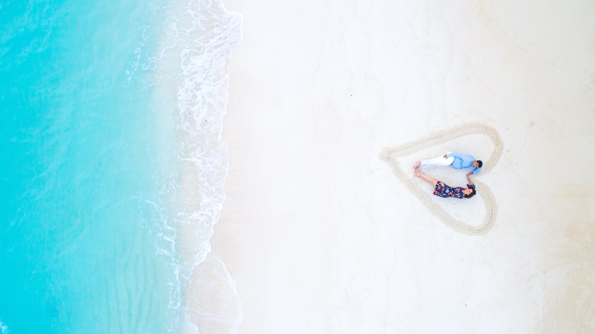 man-and-woman-lying-on-white-sand-near-sea-shore-1198839