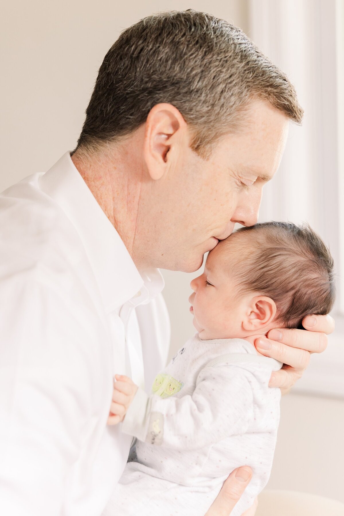 New dad kissing his baby girl's forehead