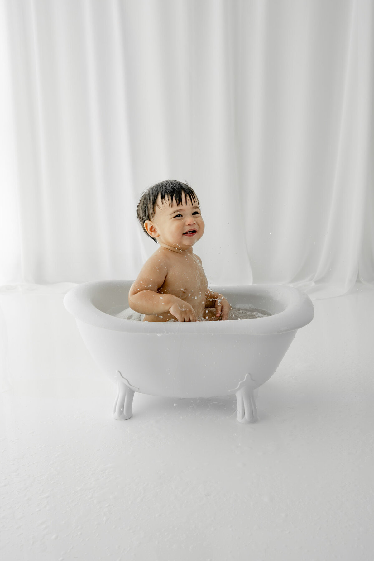 Boy in bubble bath during themed cake smash session— captured by Alliston and Barrie cake smash photographer.