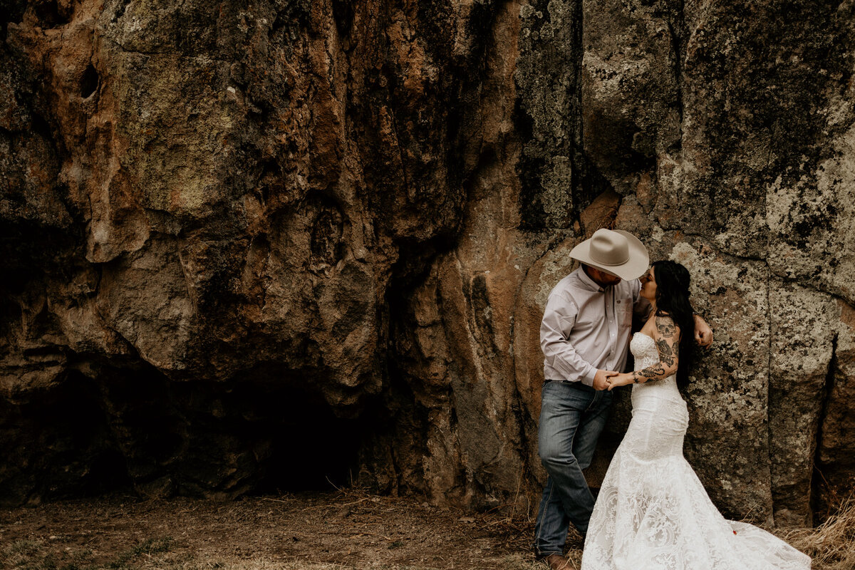 bride and groom standing against a rock in New Mexico