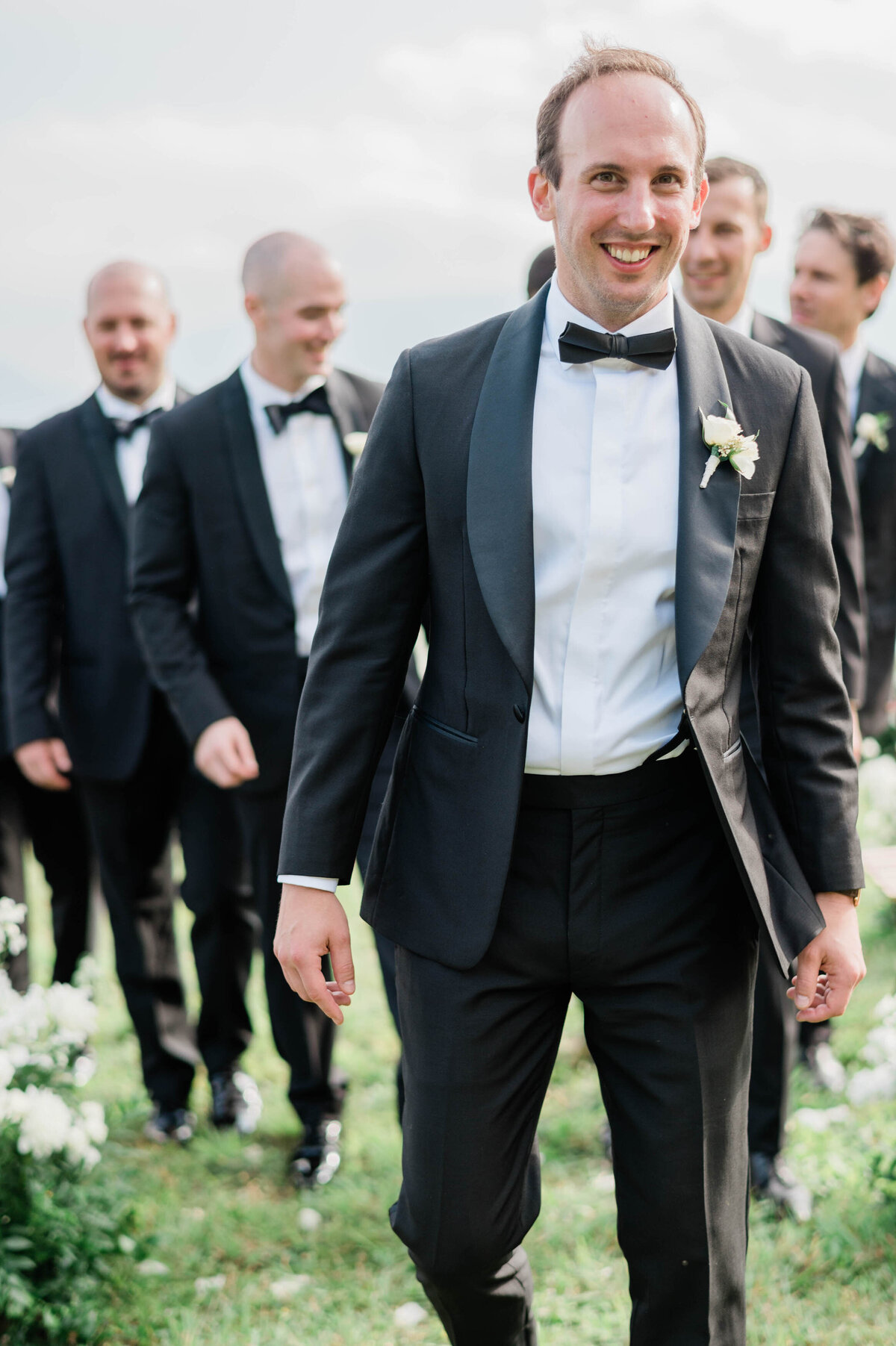 Groom walks down the aisle ahead of groomsmen