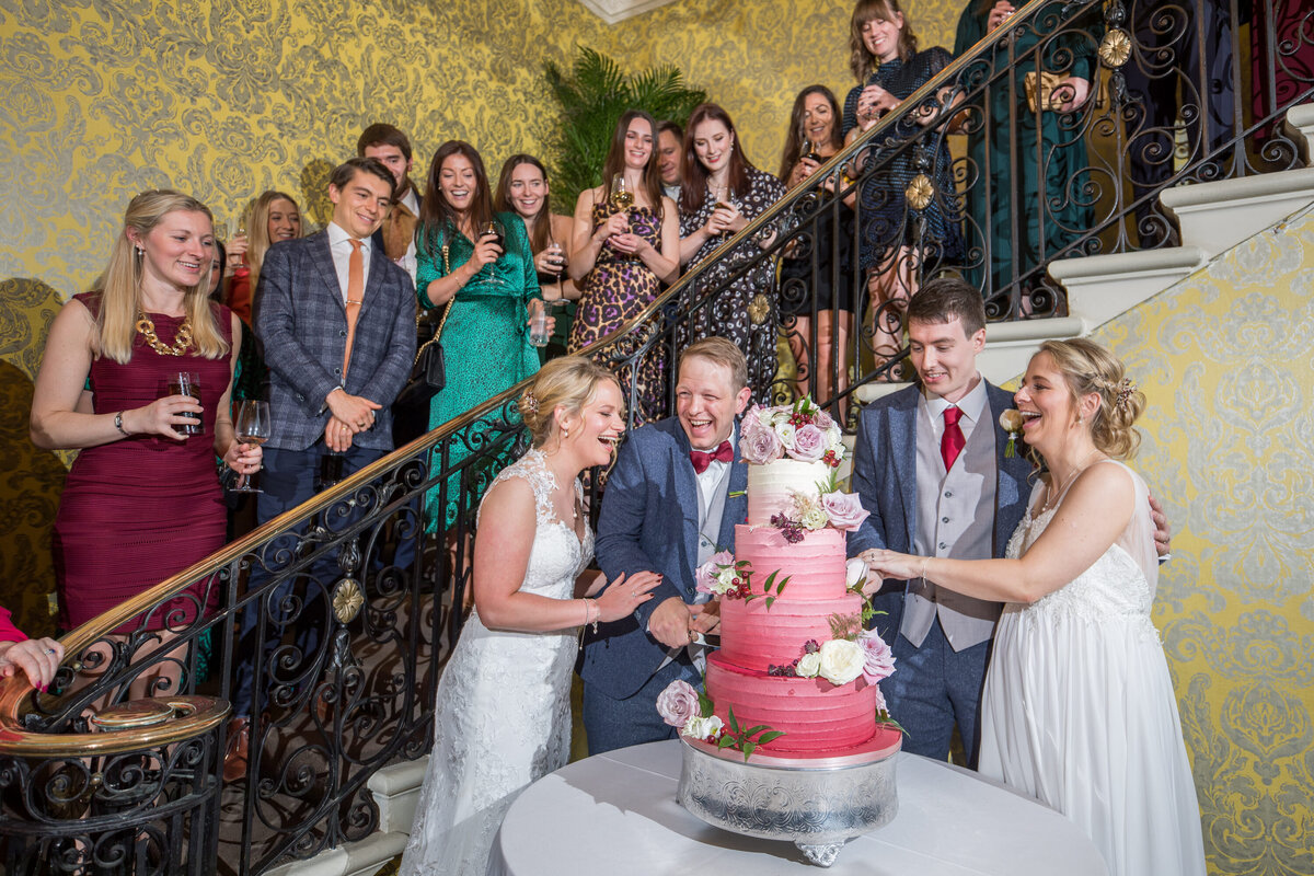 cake cutting at wedding reception with family on staircase