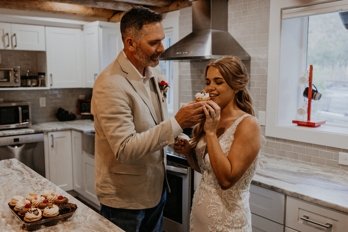 newlyweds enjoying cupcakes together in their kitchen after their ceremony