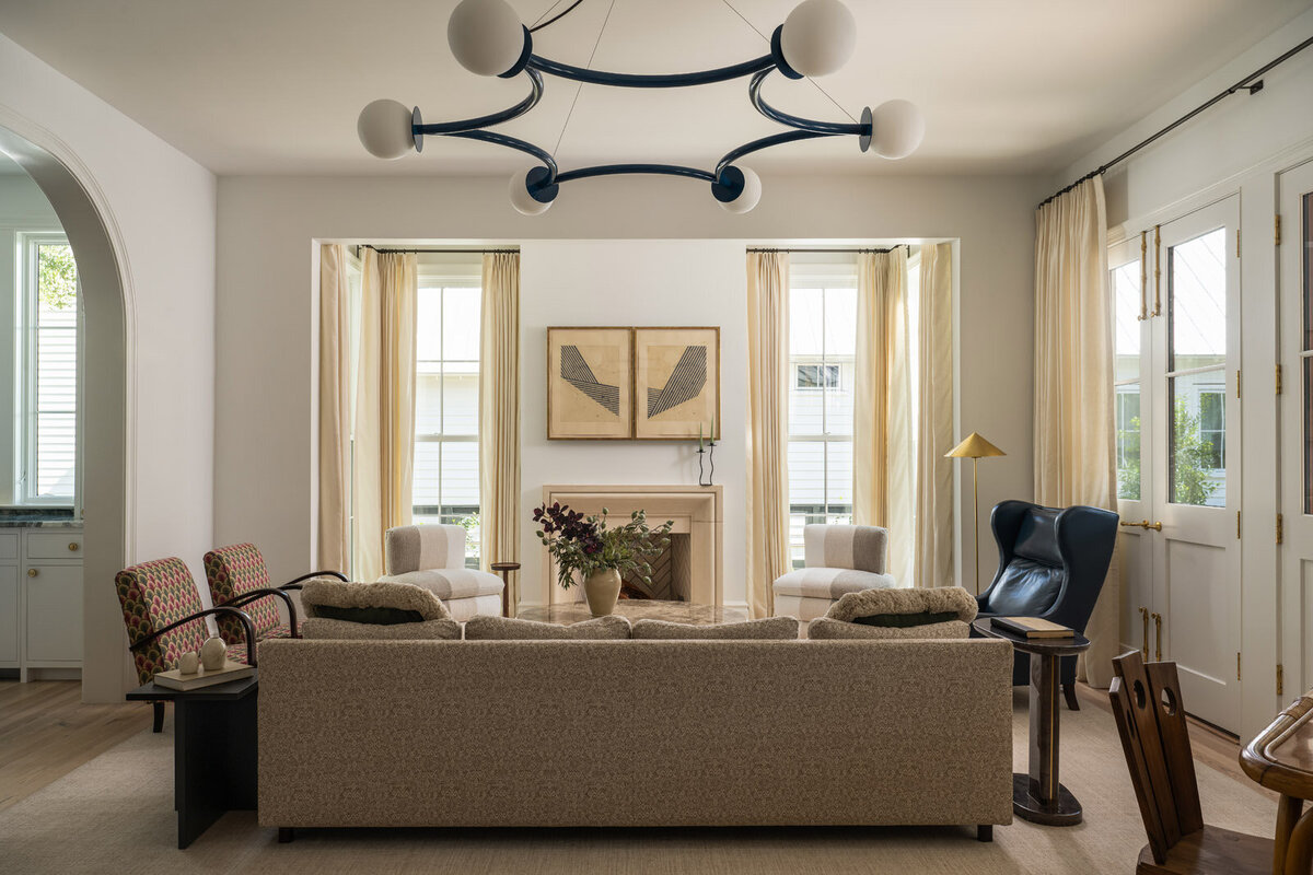 Bold living room with beige couches, green velvet ottoman and patterned artwork