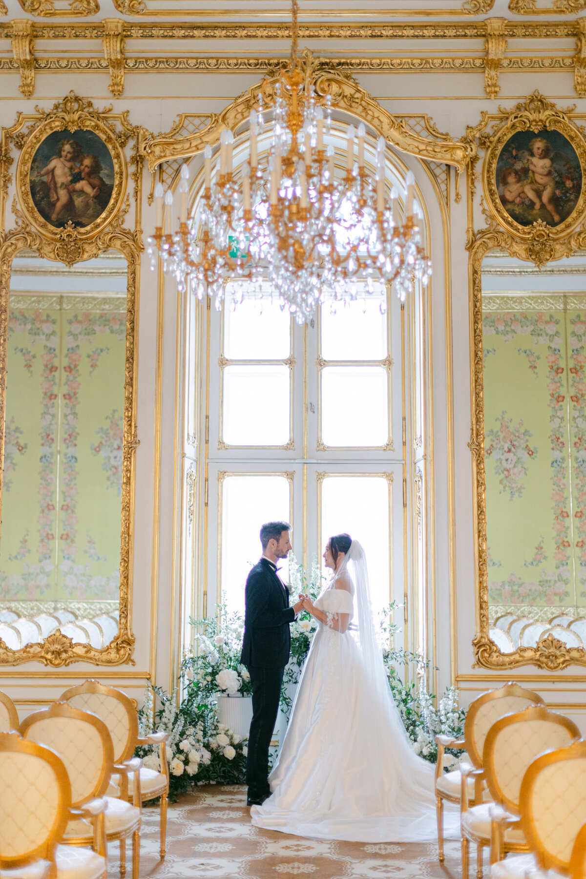 Destination wedding couple holding hands in yellow room of luxury wedding palace Coburg in Vienna