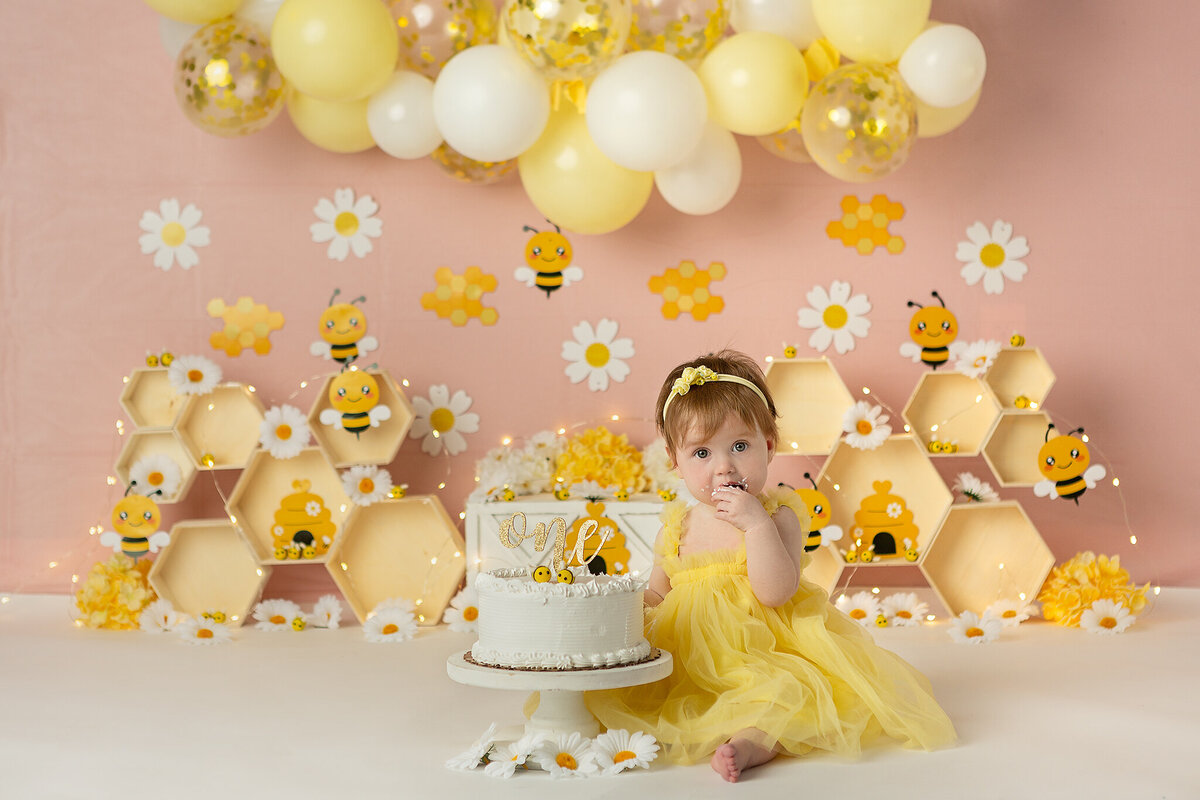 columbus-ohio-first-birthday-baby-girl-in-yellow-tulle-dress-with-pink-backdrop-bumblebee-honey-sweet-as-can-bee-theme-cake-smash