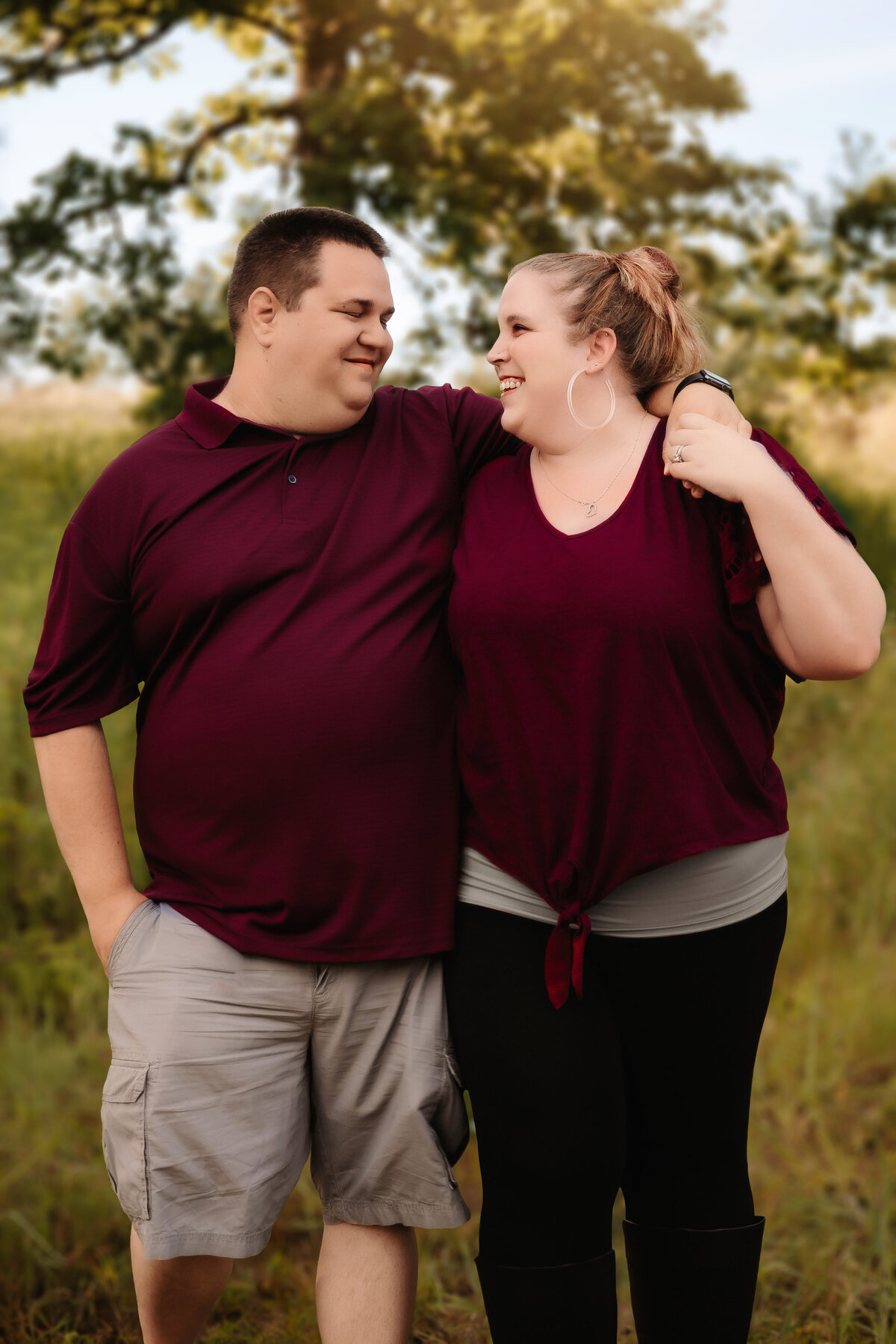 This couple stands side by side while posing in a field for their engagement photos.