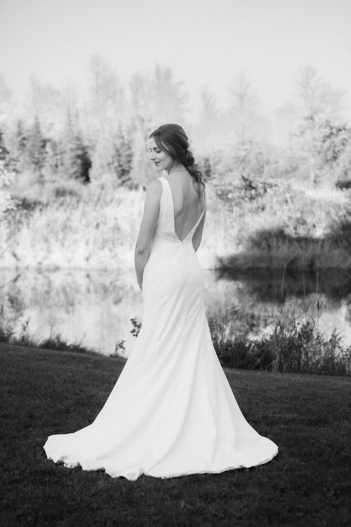 black and white portrait of a bride posing to show the details of her dress