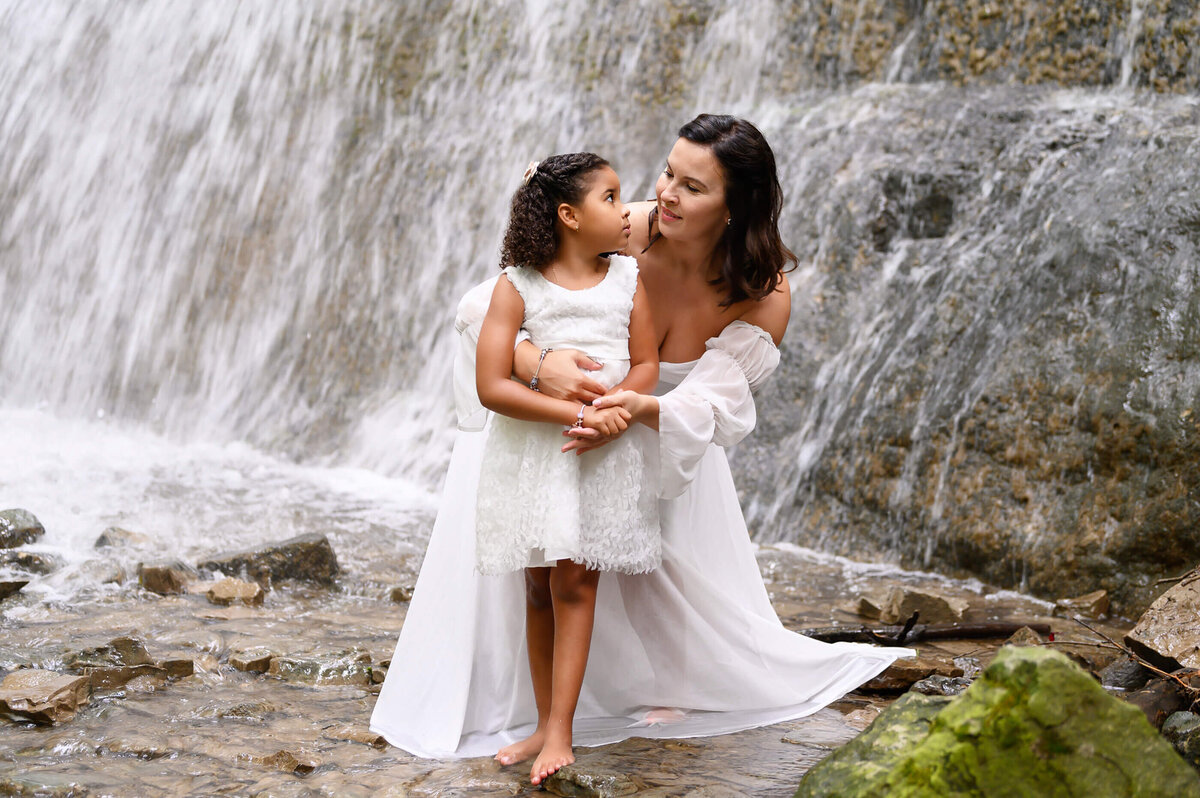 Mom and daughter wearing white at a waterfall for their Burlington family photography session