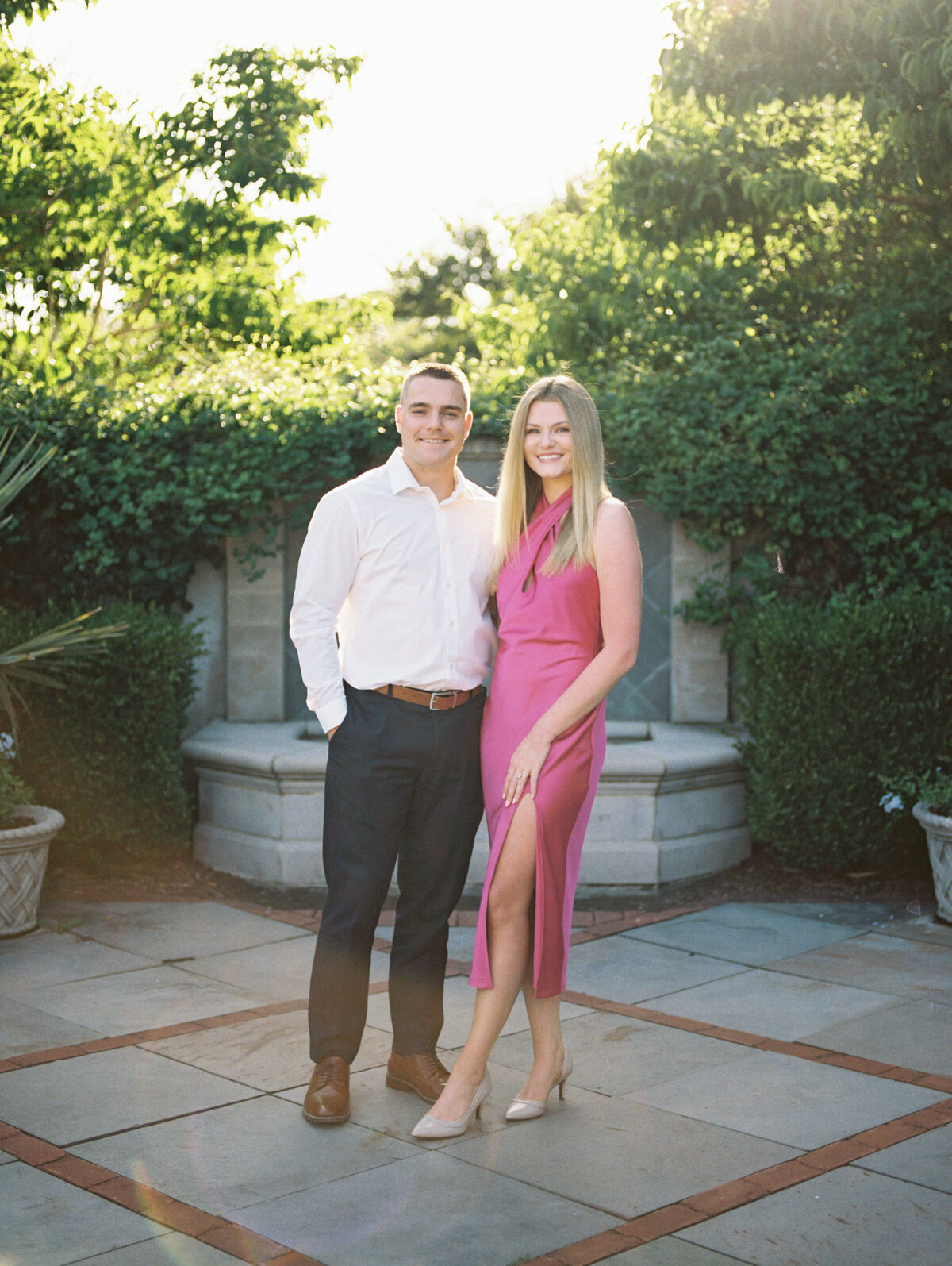 Engaged couple smiling in front of Columbus park fountain shot by Philadelphia photographer.