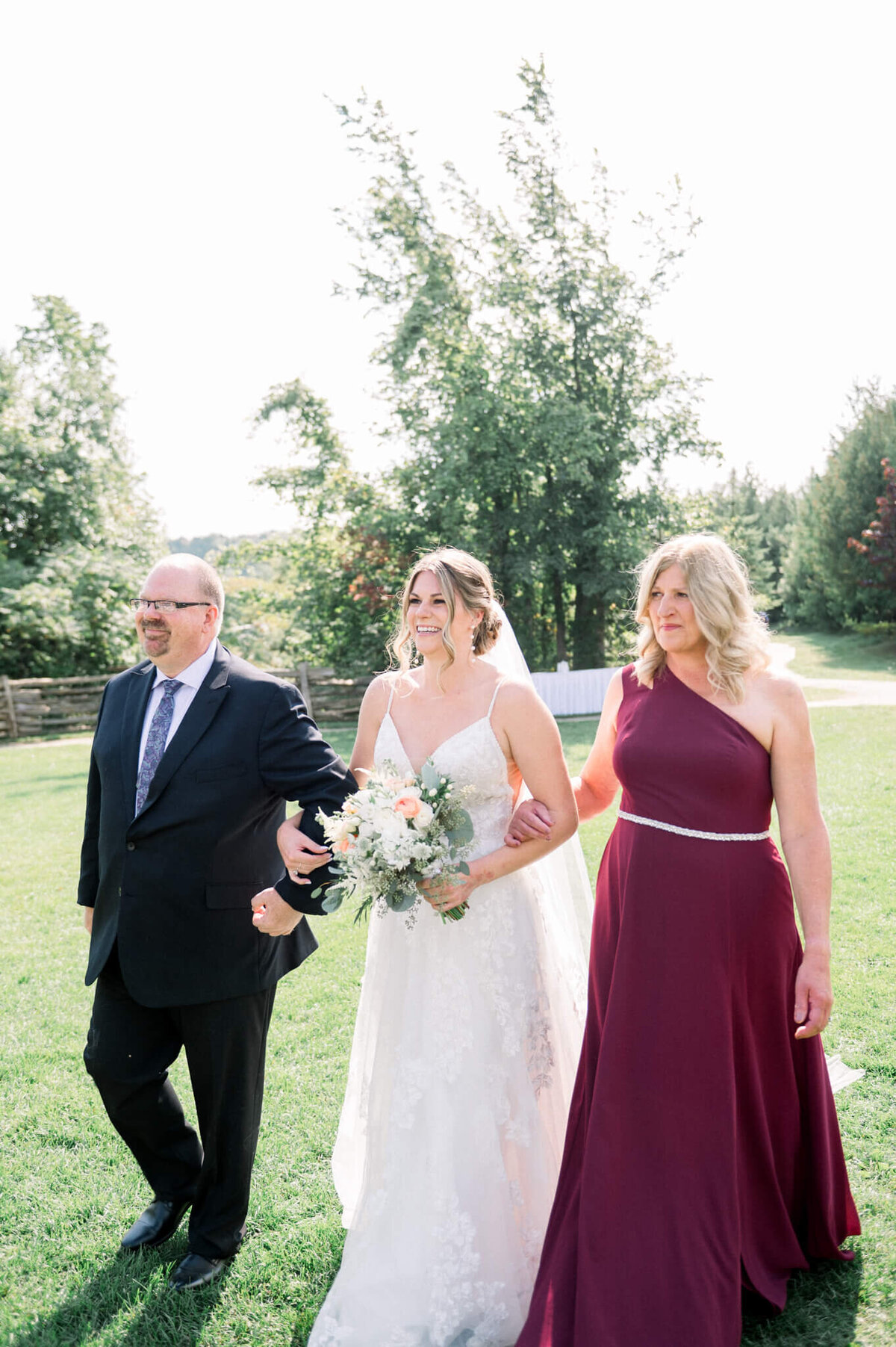 Bride walking down the aisle with parents captured by Niagara wedding photographer