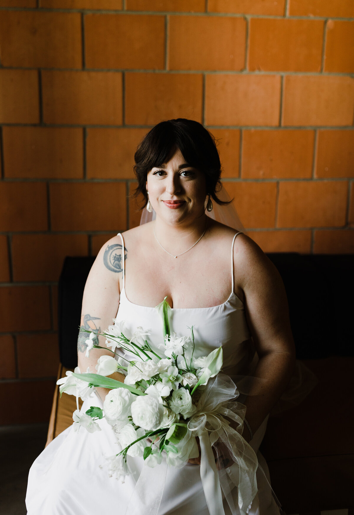 Bride sitting down holding bouquet of white flowers