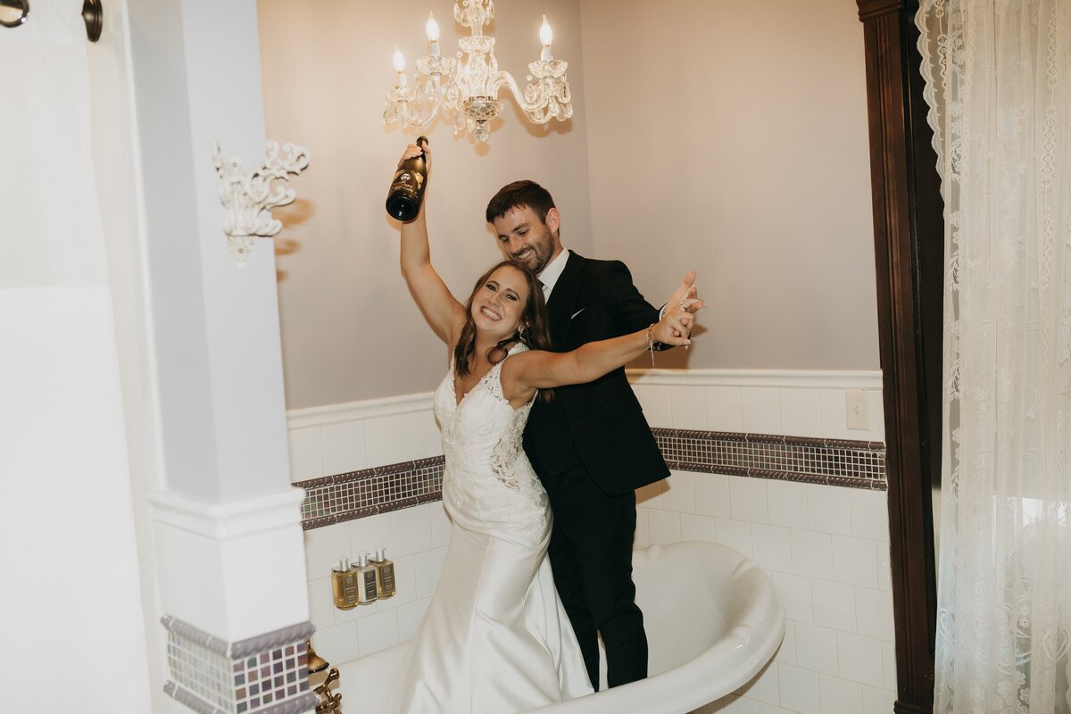 bride and groom popping bubbly in bathtub