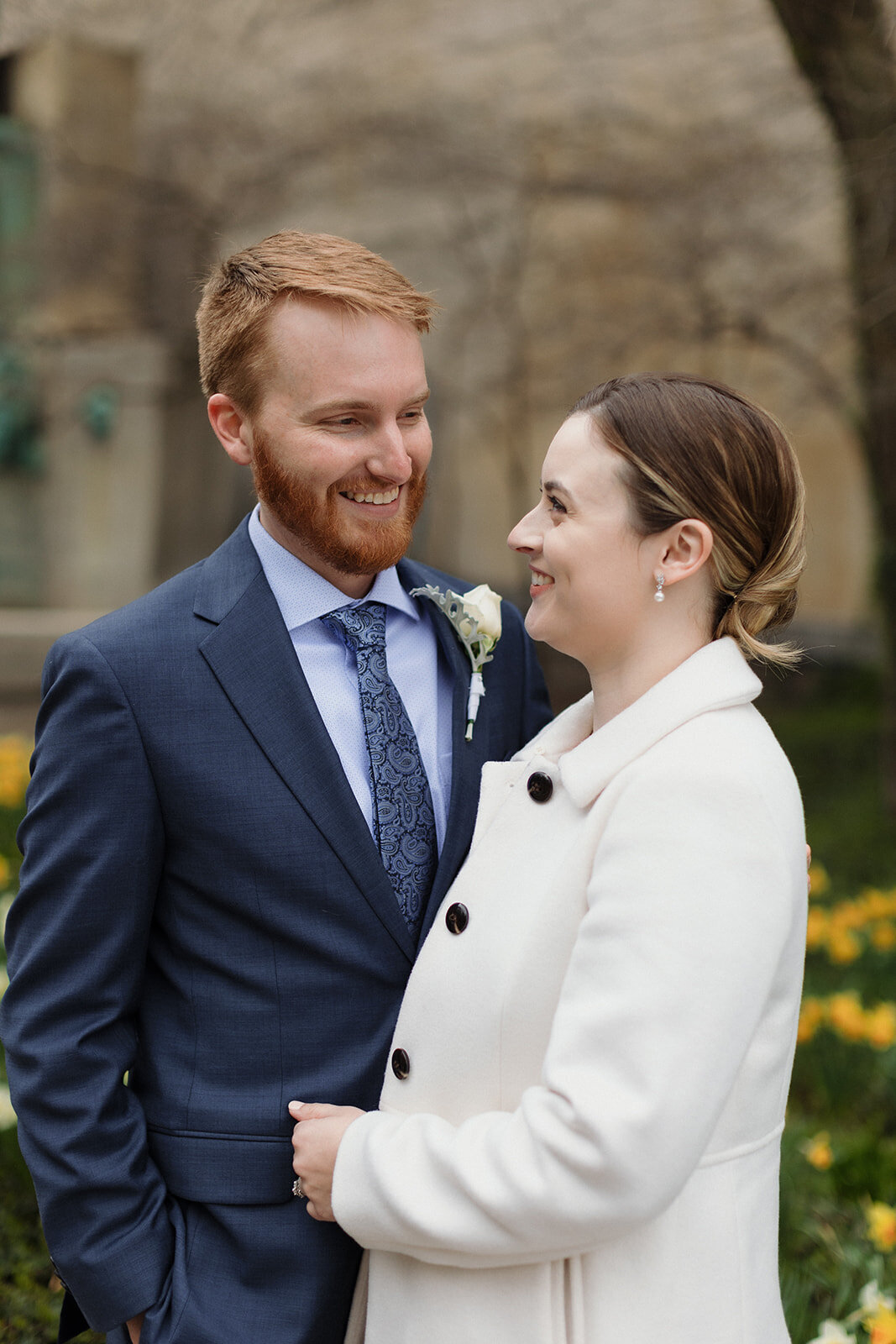 Just Married photo session couple standing in garden of yellow daffodils and smile at each other