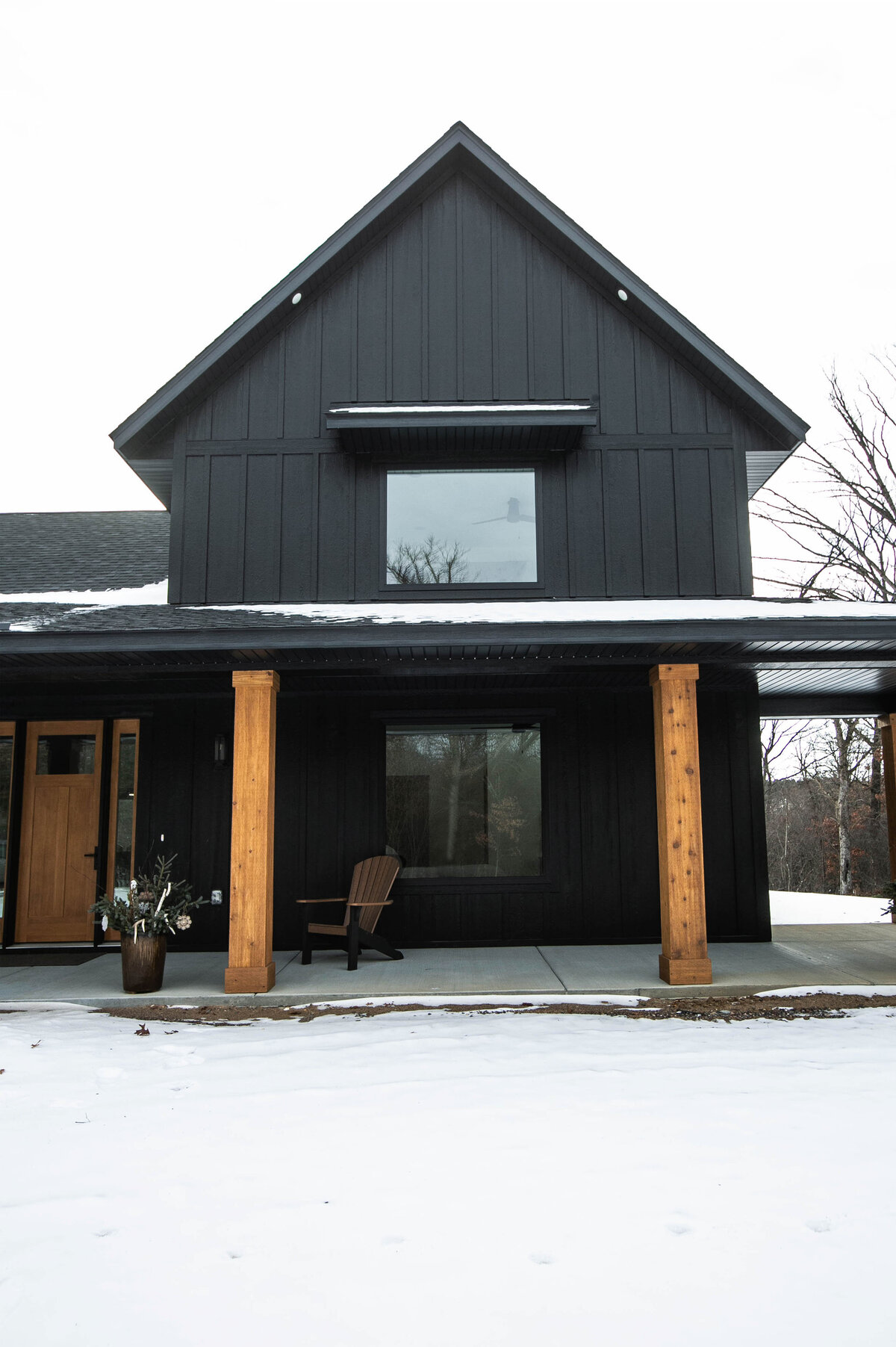 Exterior view of custom home in Elk River, Minnesota with black siding, wood details and front porch built by Cornerstone Custom Builds