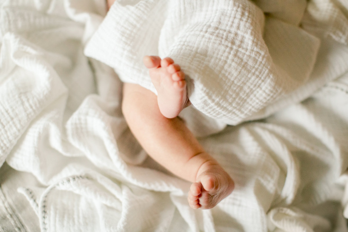 newborn baby feet in white linens on bed