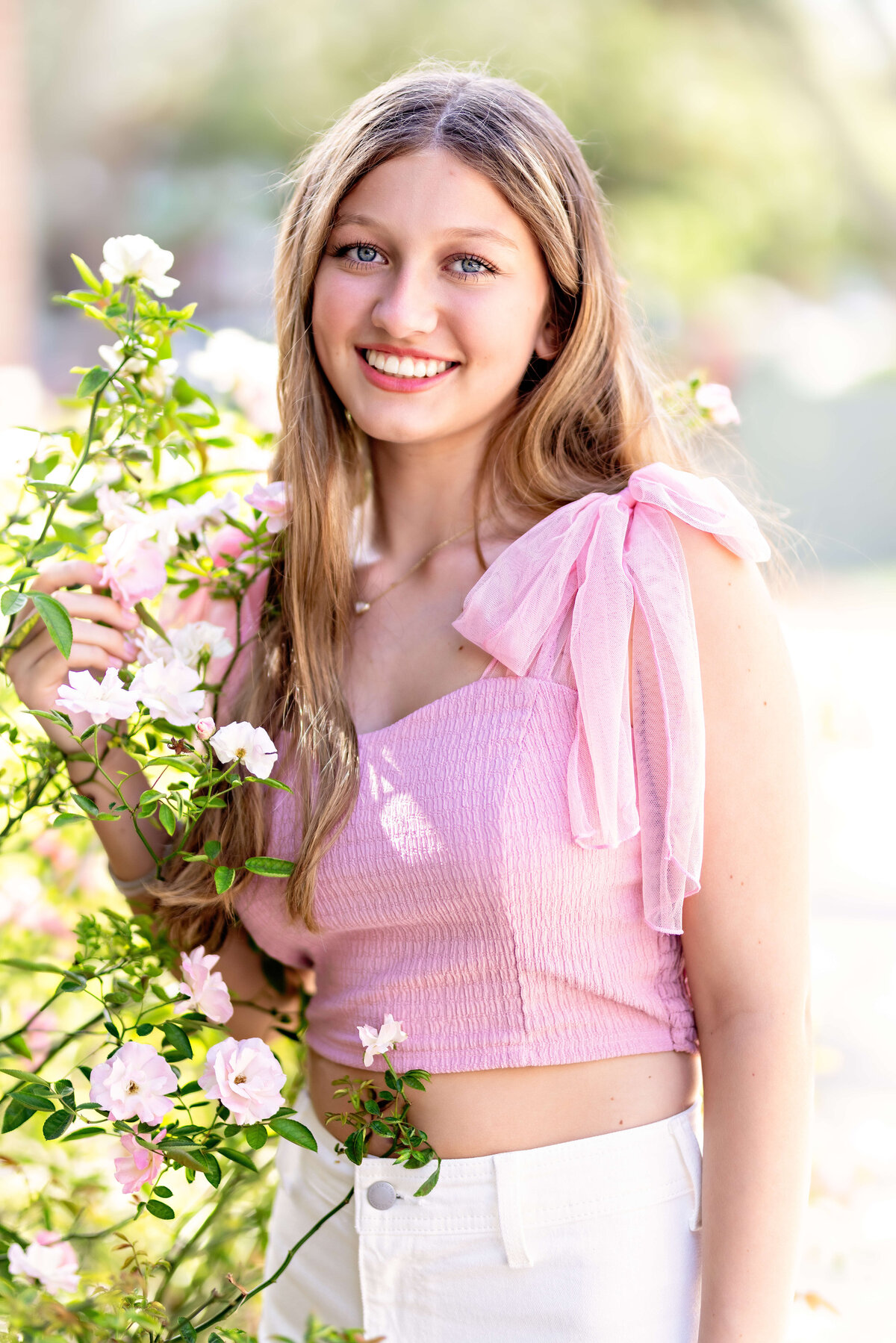 Senior girl standing by florals and smiling during Windermere, Florida portrait session