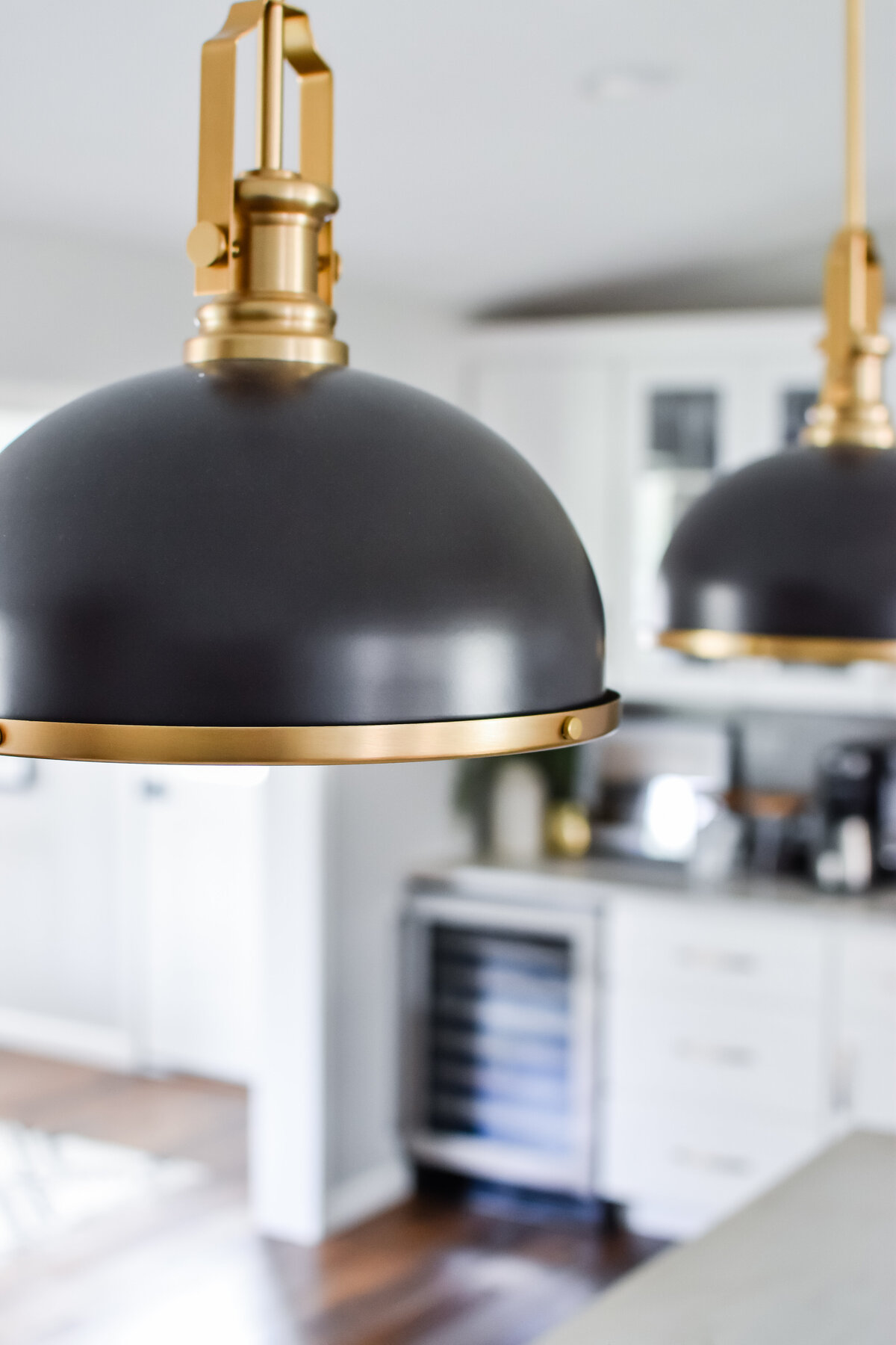 Two black metal pendant lights hang over a white kitchen island