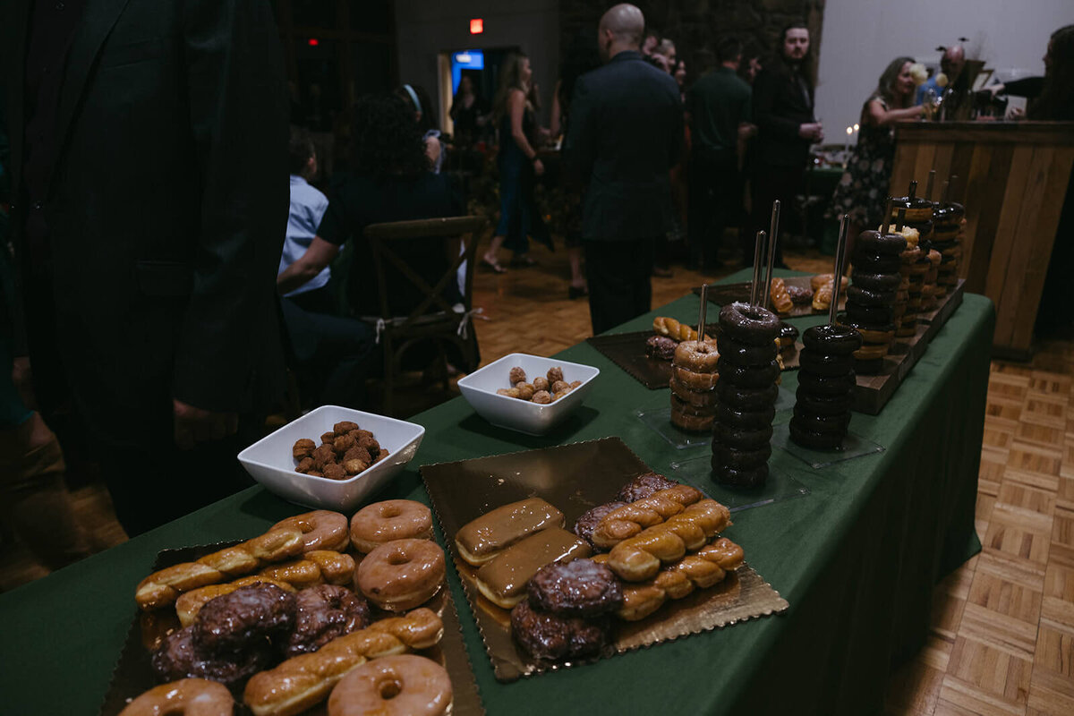 Dessert donuts spread out on a table at a fall wedding planned by Birdie June Events.