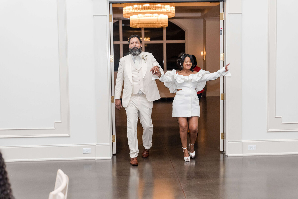 The newlyweds make a stylish entrance, holding hands as they step onto the dance floor.