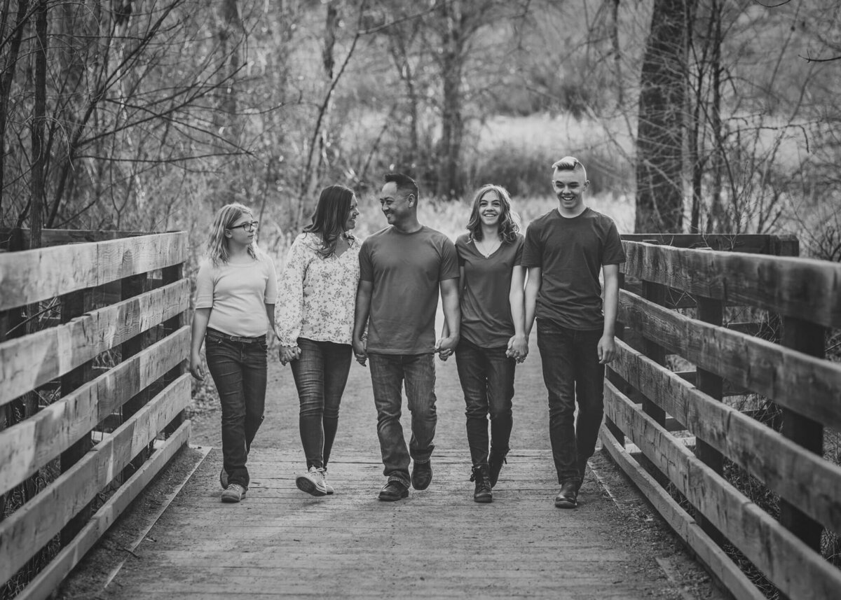 family of  five walking across a bridge together