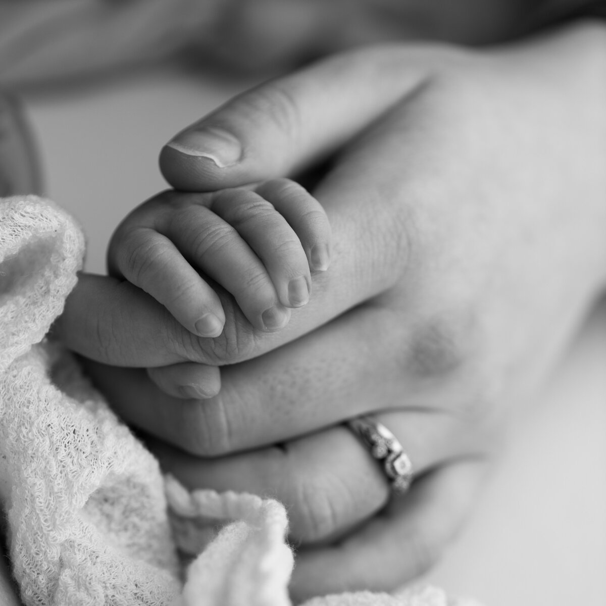 A touching macro of a newborn gripping mama’s thumb—a bond so small, yet so mighty.