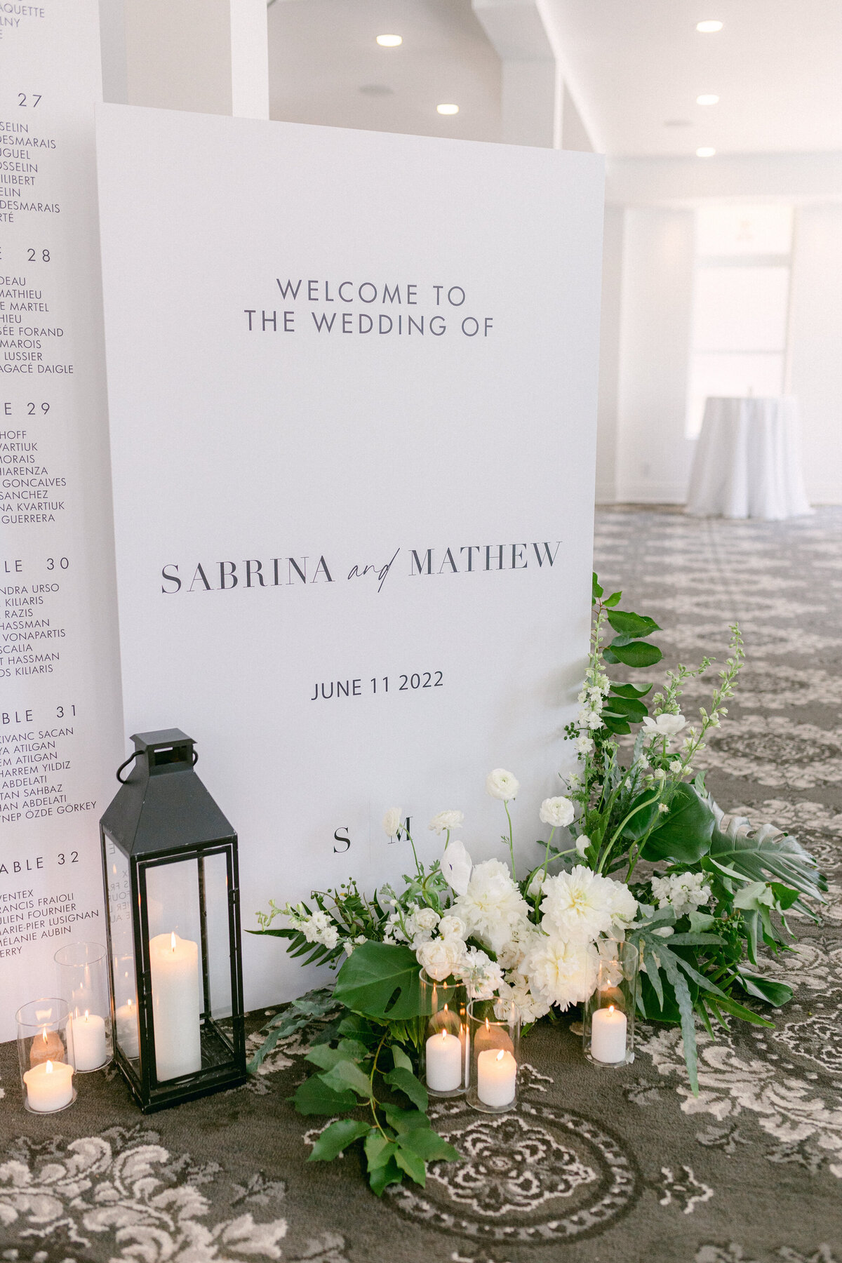 A welcome sign at a Montreal wedding reception is decorated by a lush flower arrangement. 