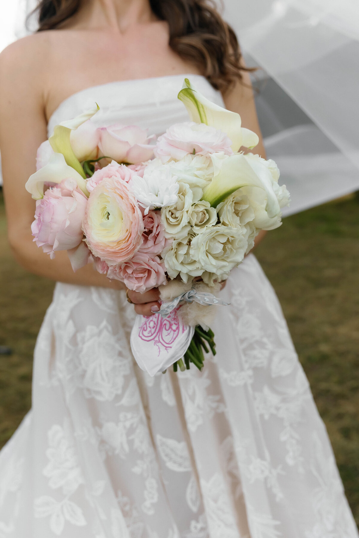 Close-up of the bride holding a lush bouquet of blush garden roses, white calla lilies, ranunculus, and textured blooms, featuring delicate floral design by an Arkansas wedding florist.
