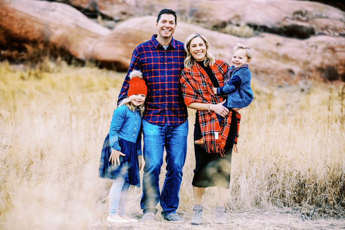 a familiy of four stand in front of red rocks in colorado