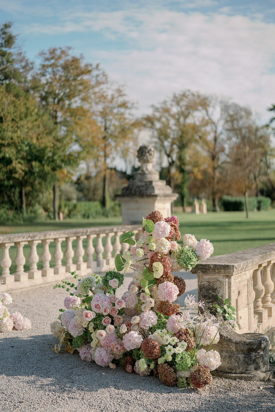 Lush pink and blush floral arrangements decorating stone terrace at Château de Tourreau wedding.