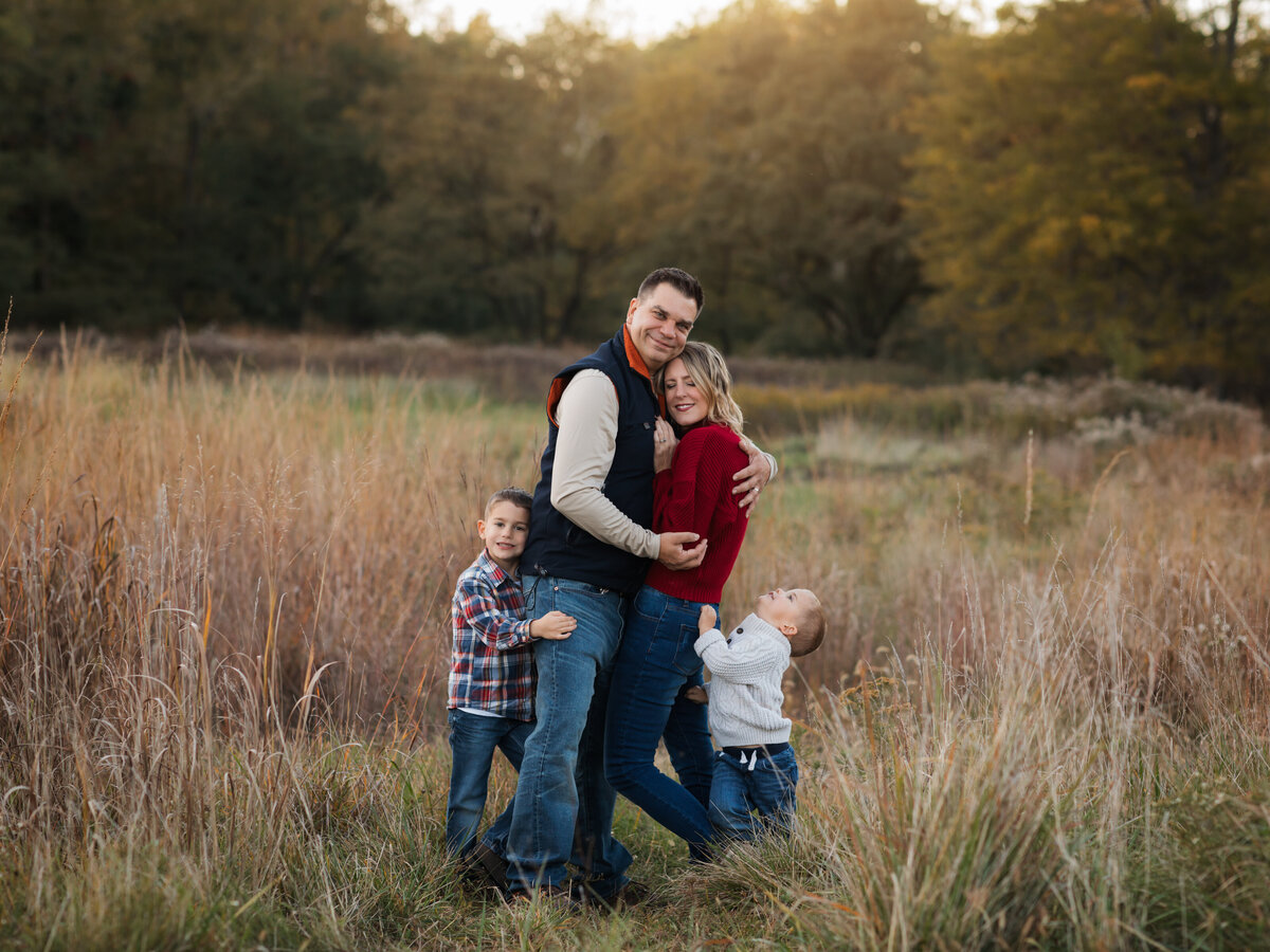 mom dad and two sons posed in field for family photoshoot cleveland family photography