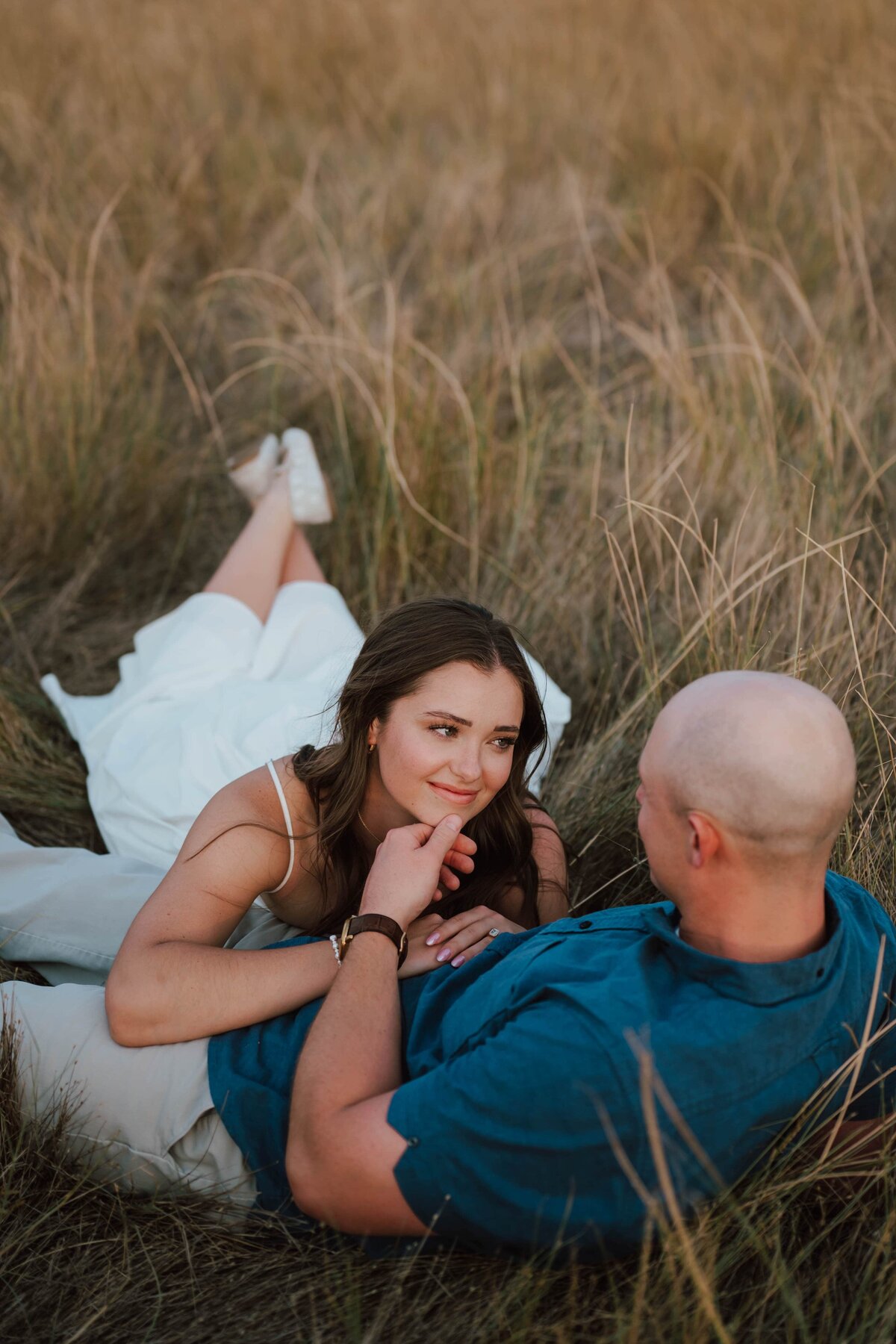 couple-engaged-laying-grass-min