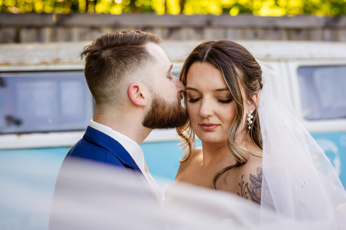 Intimate moment with groom whispering in brides ear as vail swoops past them