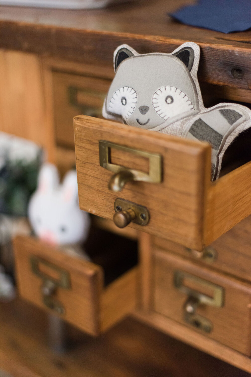 A fabric squirrel peeks out of a drawer on the dessert table at a woodland-themed baby boy shower, adding a playful touch to the enchanting rustic decor that brings you closer to nature.