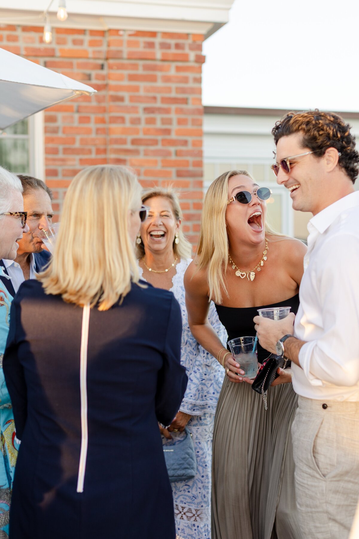 guests laughing during welcome drinks on the lawn of American Yacht Club