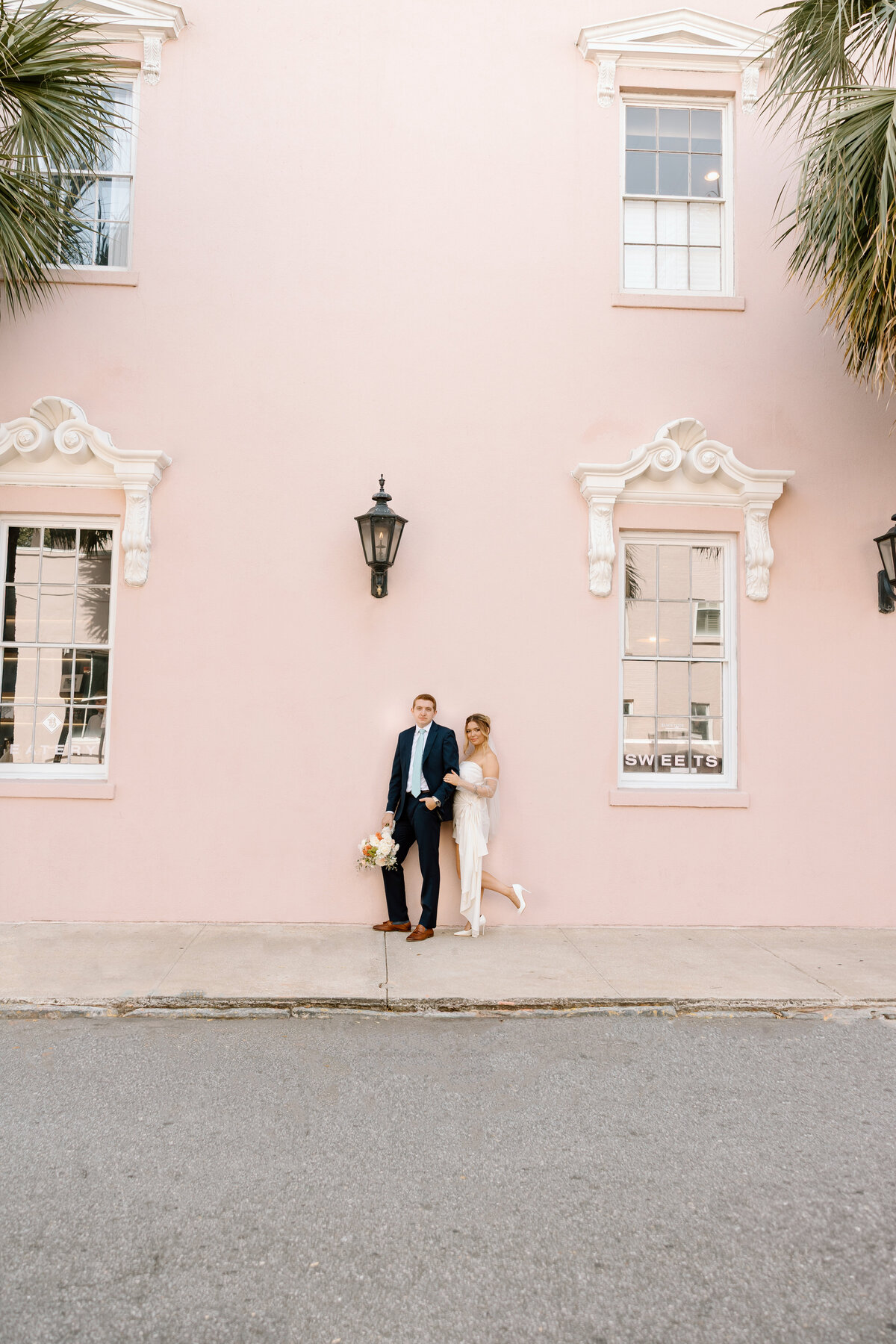 Couple posing in front of Charleston’s iconic pink wall during an intimate downtown elopement.
