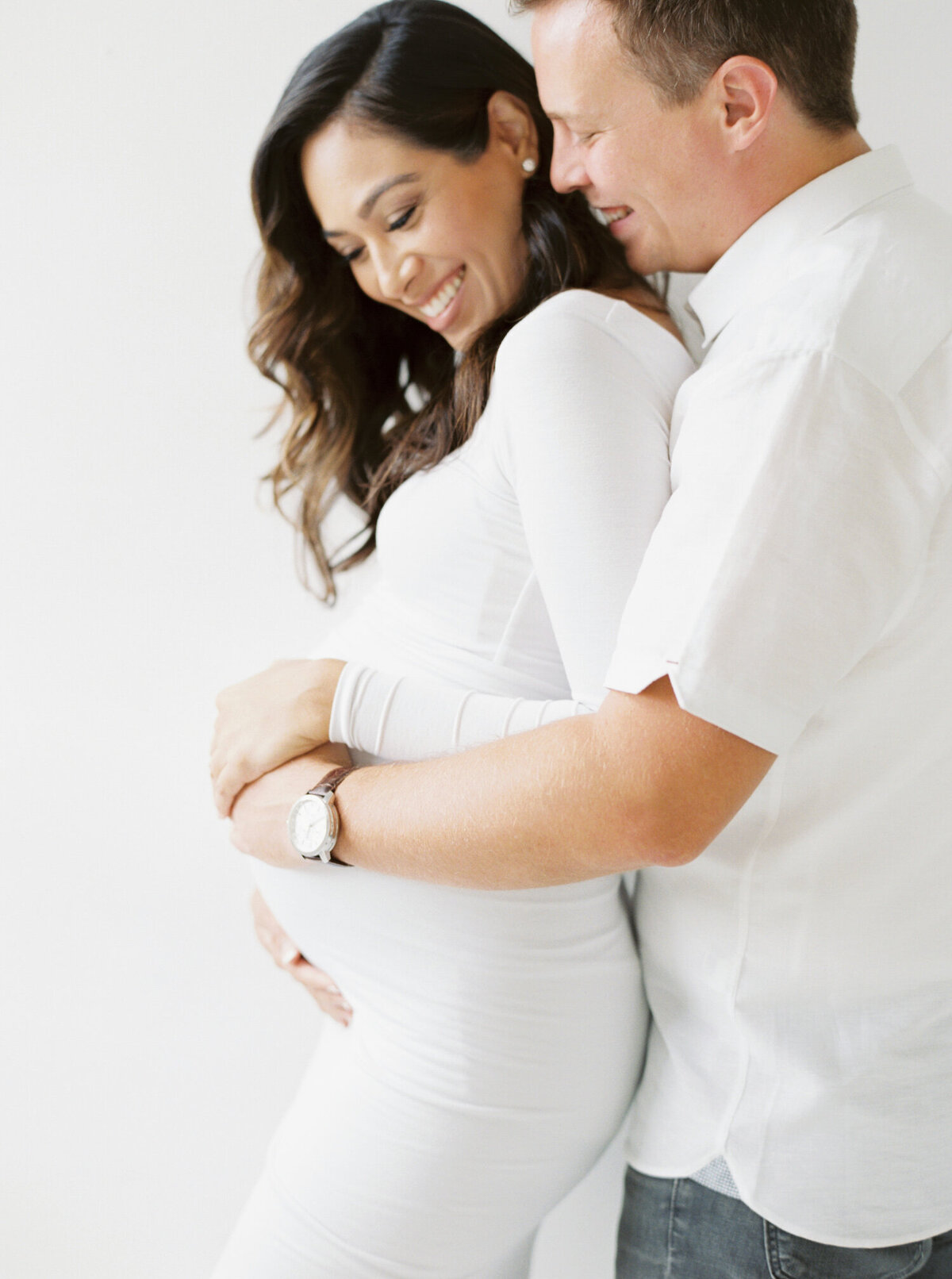 couple wearing all white in white studio captured by Seattle Maternity Photographer Brittany Carvalho