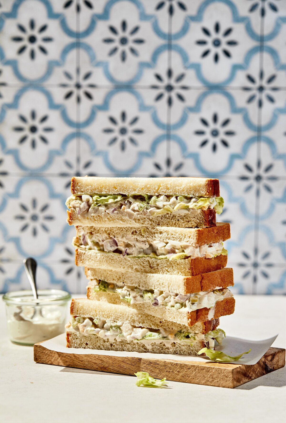 A stack of tuna fish sandwiches on a small wood block.